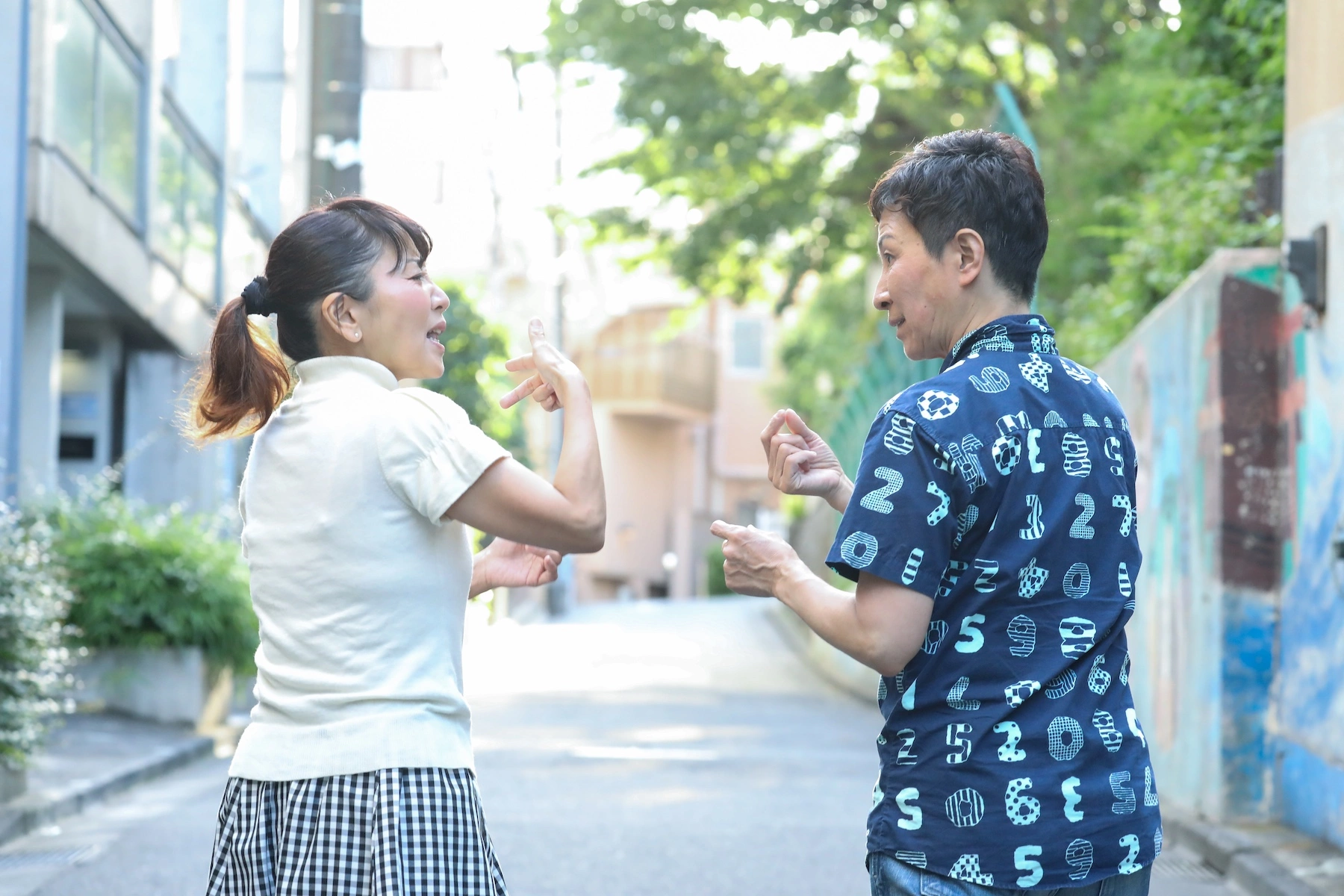 A middle age couple walks down an alley together in Japan communicating in sign language