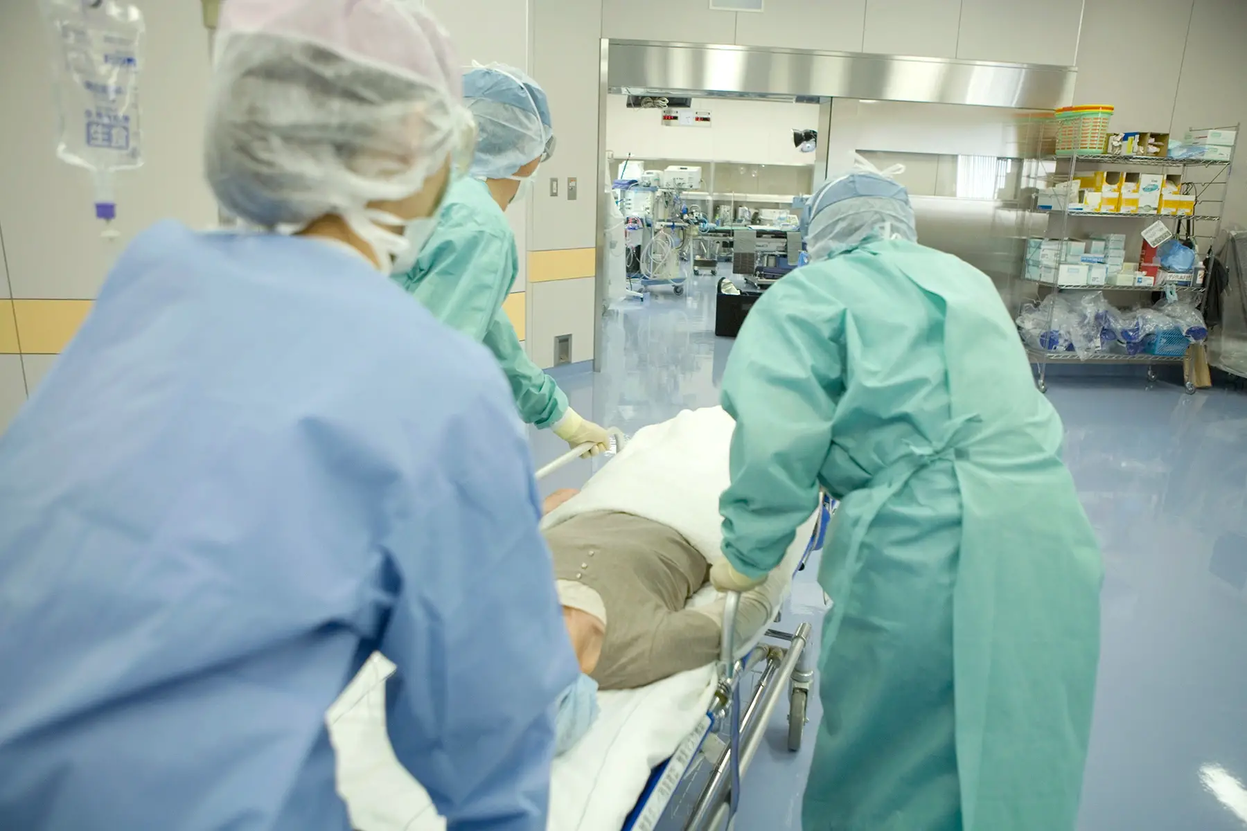 Doctors push patient on a gurney to an operating room