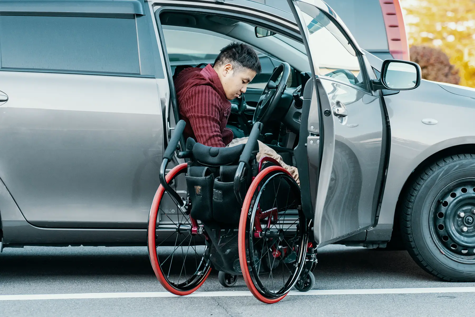 A wheelchair user getting out of his chair into the driver seat of a car