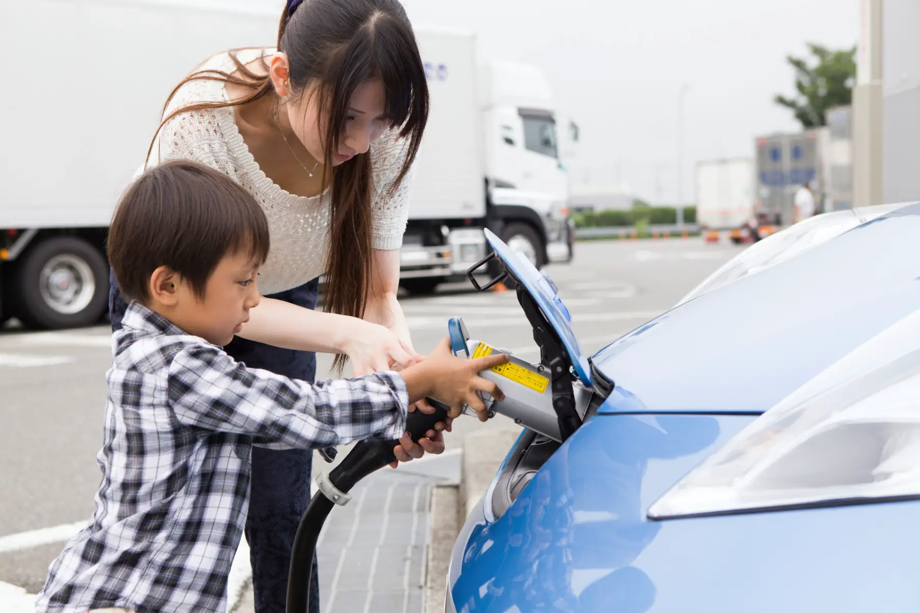 a mother showing her little boy how to charge their electric vehicle 