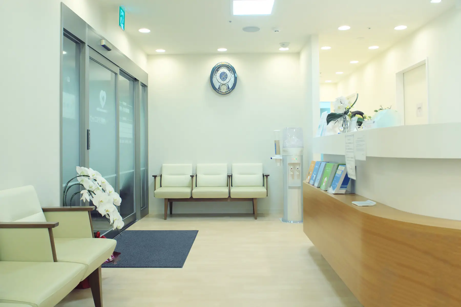 An empty doctor's office waiting room in Japan, with flowers, water cooler, and a reception desk