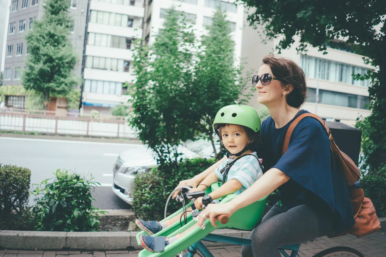 Mother cycling with toddler daughter on the steering wheel.