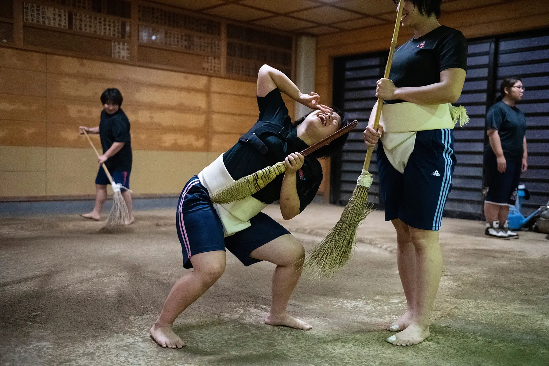 Members of Asahi University women's sumo team joke around as they sweep the dohyo (sumo ring) after a training session 