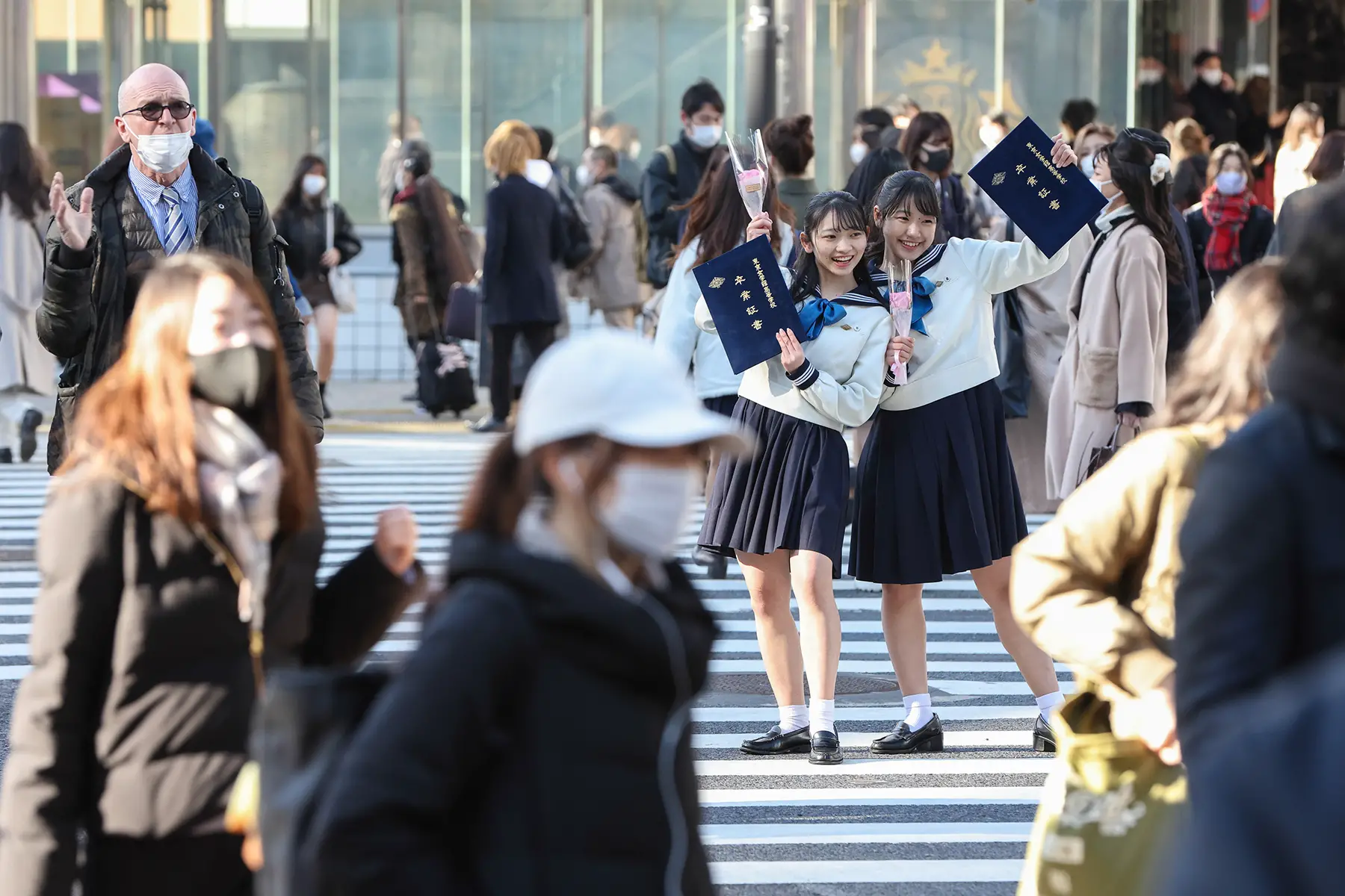 High school students pose with their graduation certificates on a crosswalk
