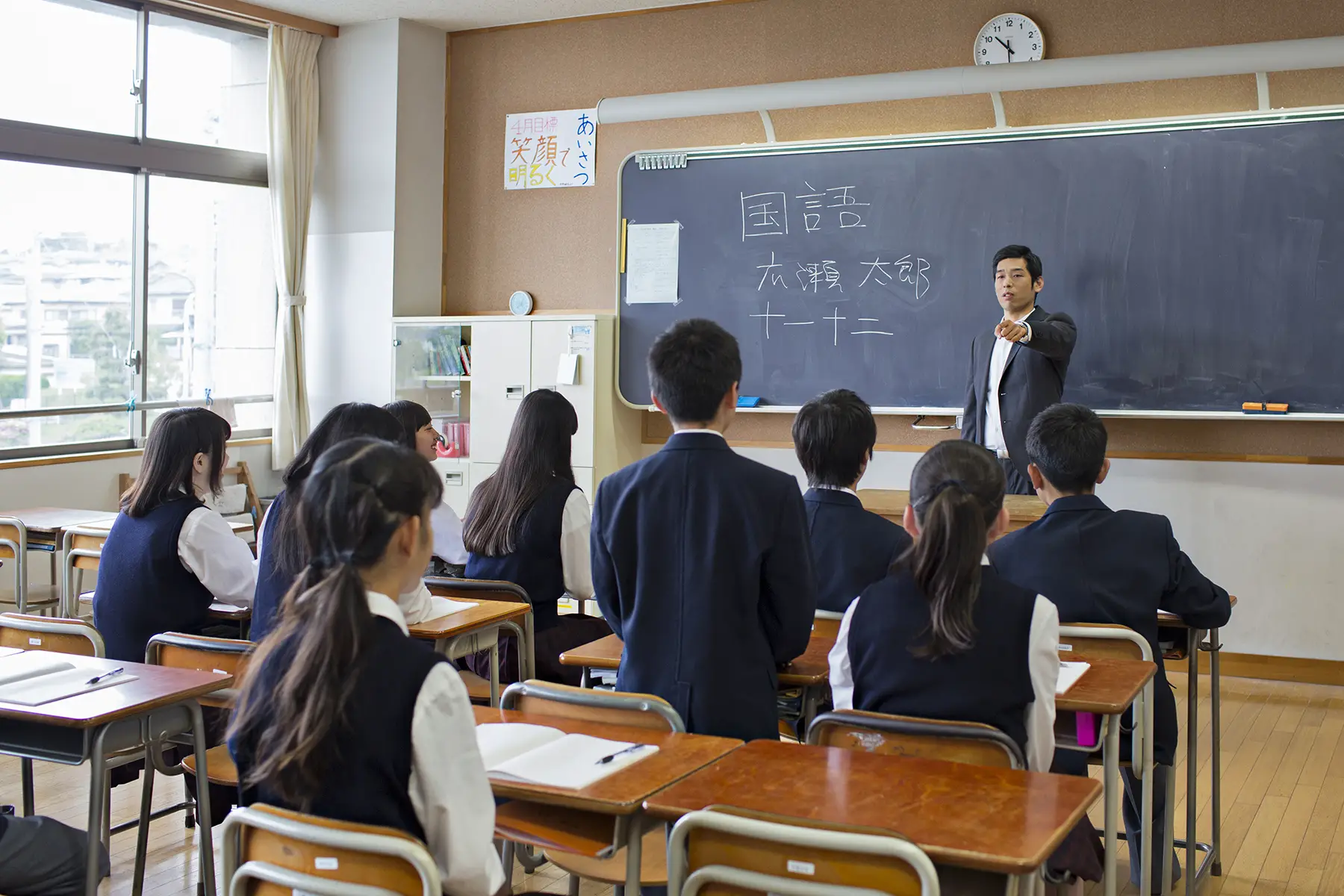 A teacher standing in front of a high school class answering student questions in Japan