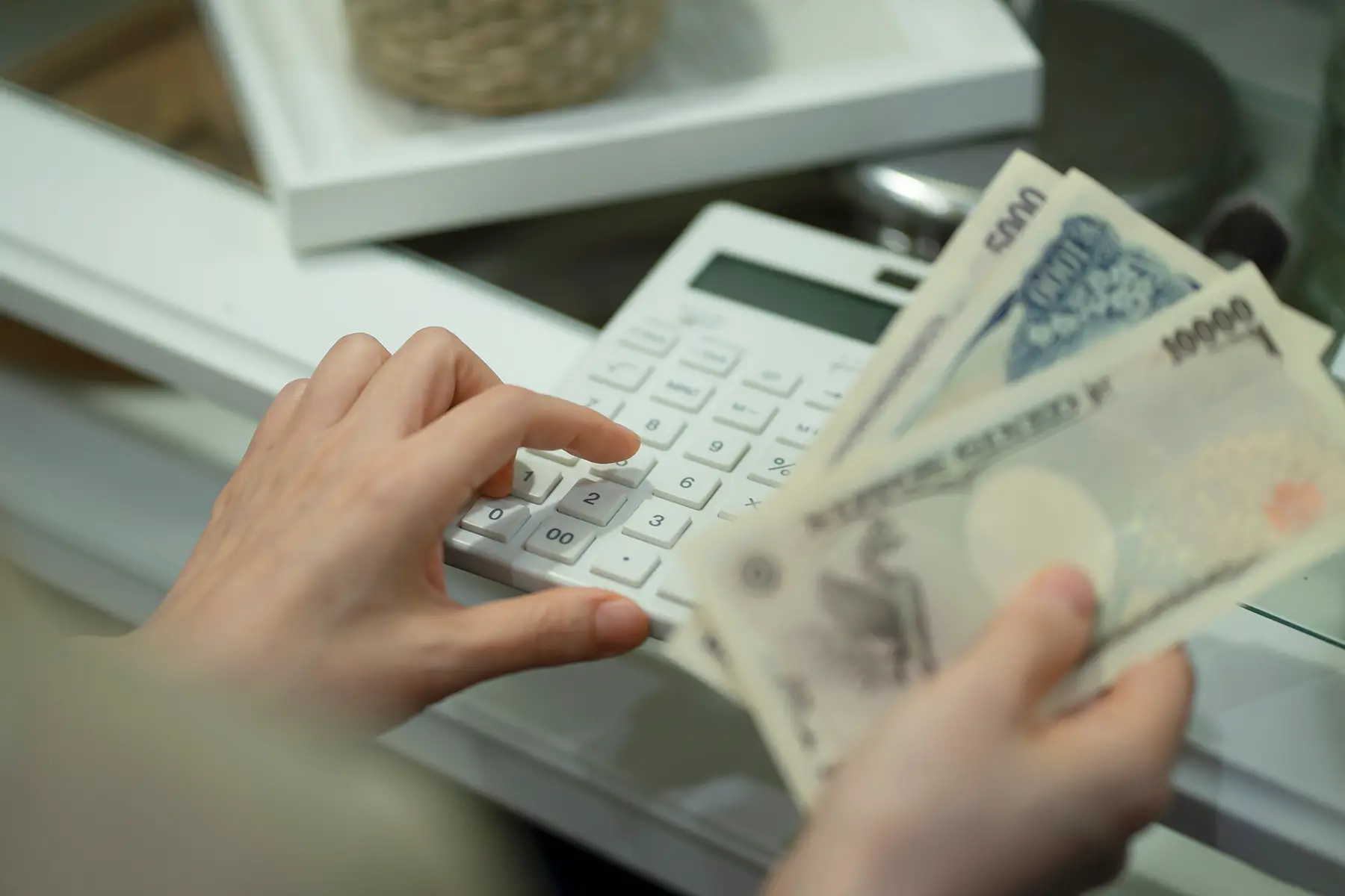 Close-up of hands holding cash and using a calculator