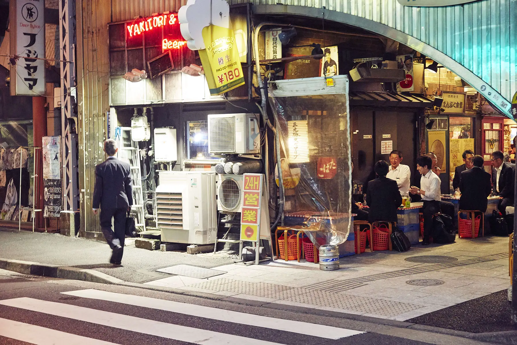 A Japanaese worker or salaryman heads home late at night past a neighborhood yakitori bar