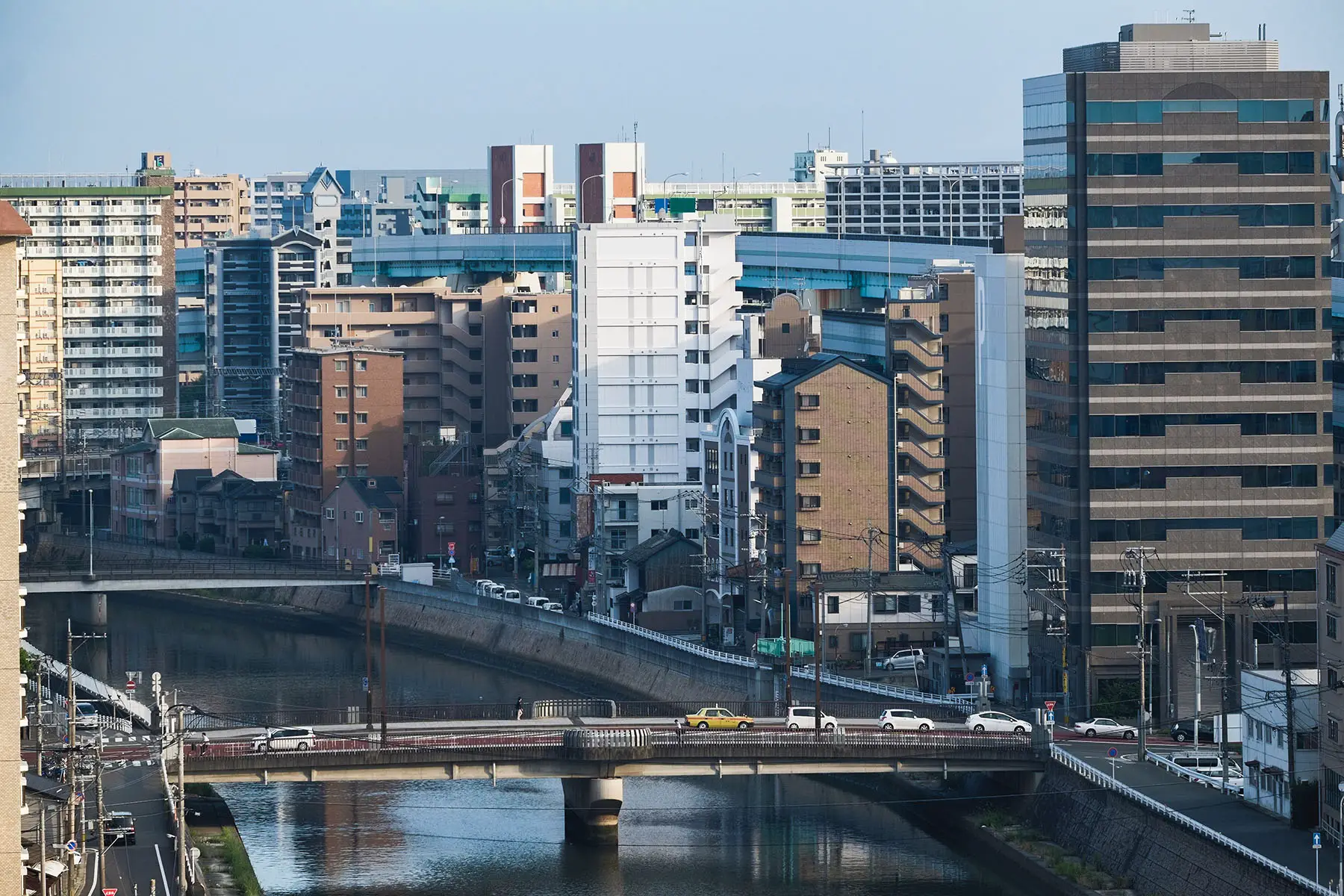 Cars driving across a bridge to the other side of a canal in Fukuoka, Japan.