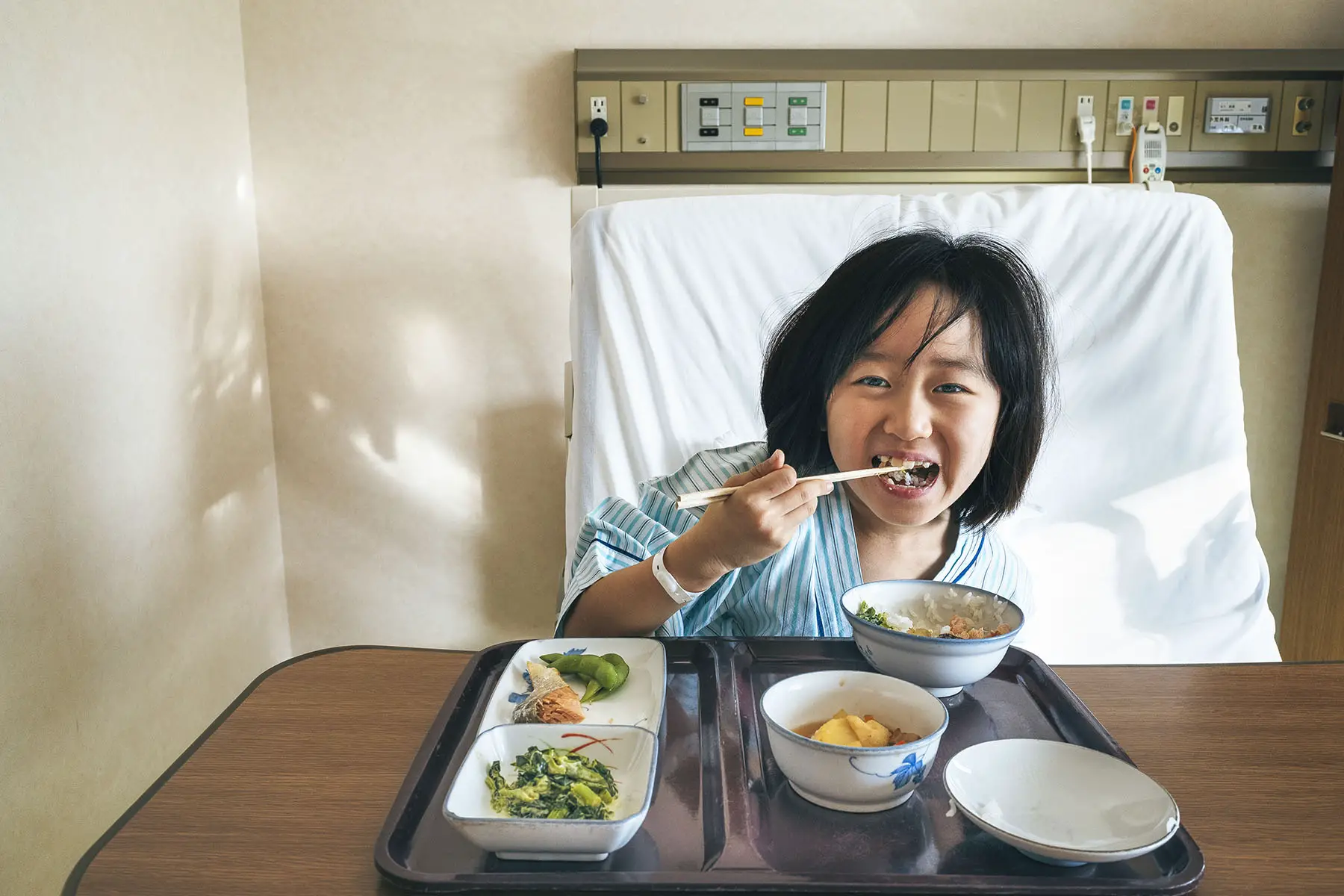 Little girl eating in her hospital bet, looking adorable.