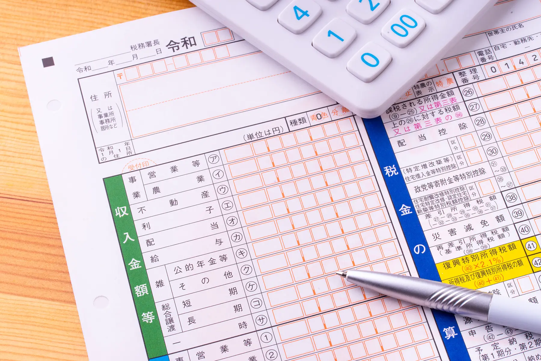 Japanese income tax form with a white calculator and a white pen