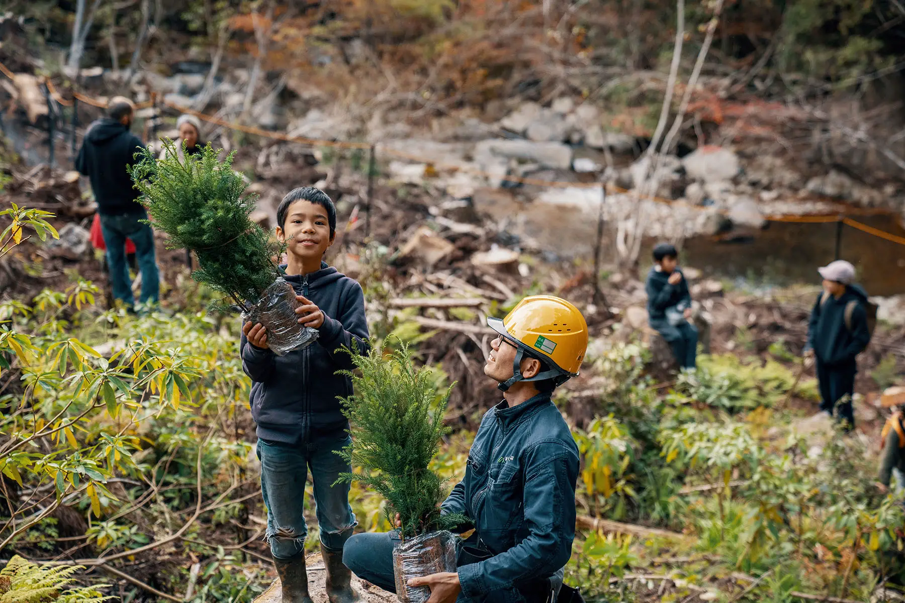 Young boy volunteering to plant seedlings at a reforestation event at a logging site in Japan