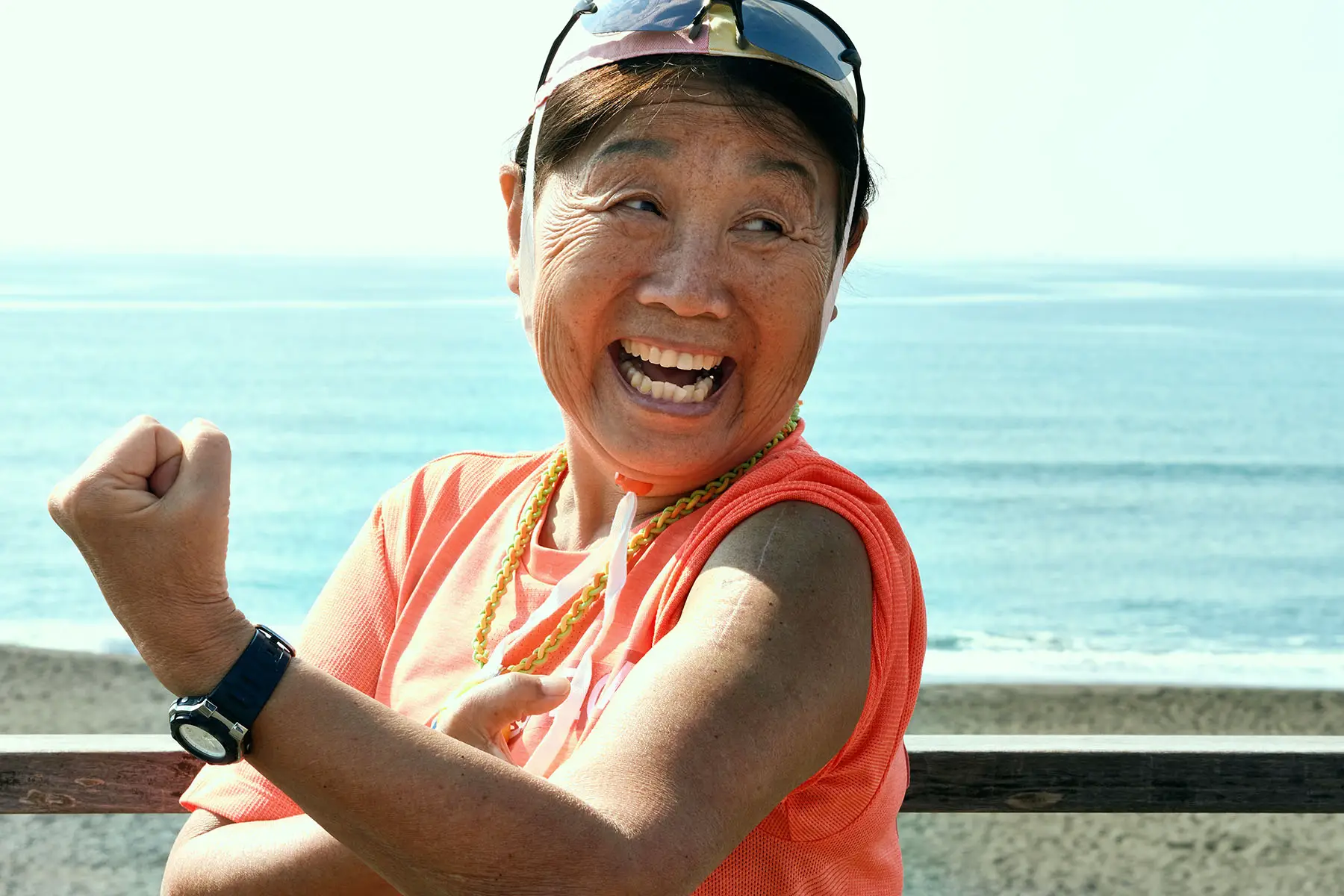 Person is laughing and showing their muscles while near the beach.