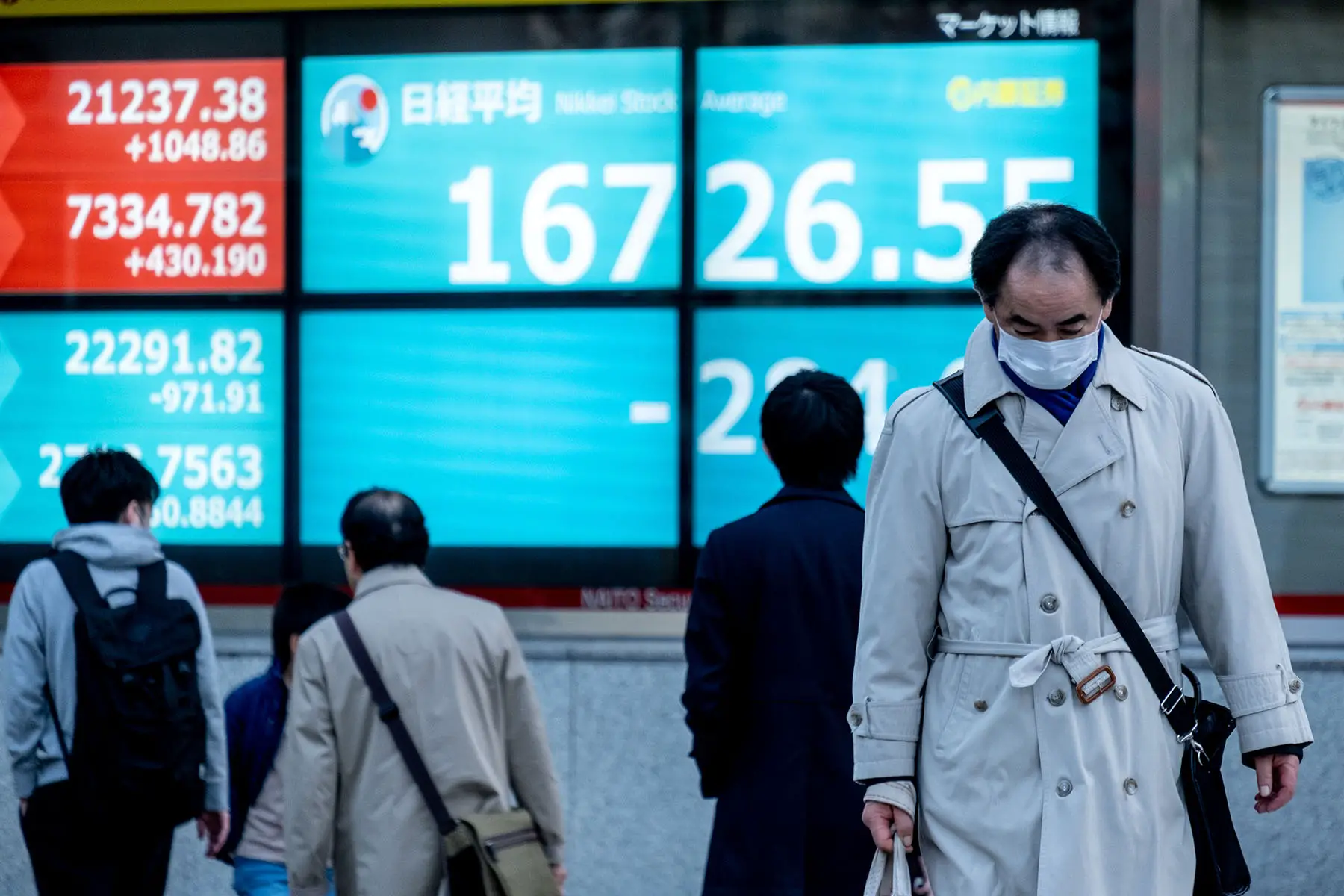 People passing by a huge stock board in Tokyo, Japan.