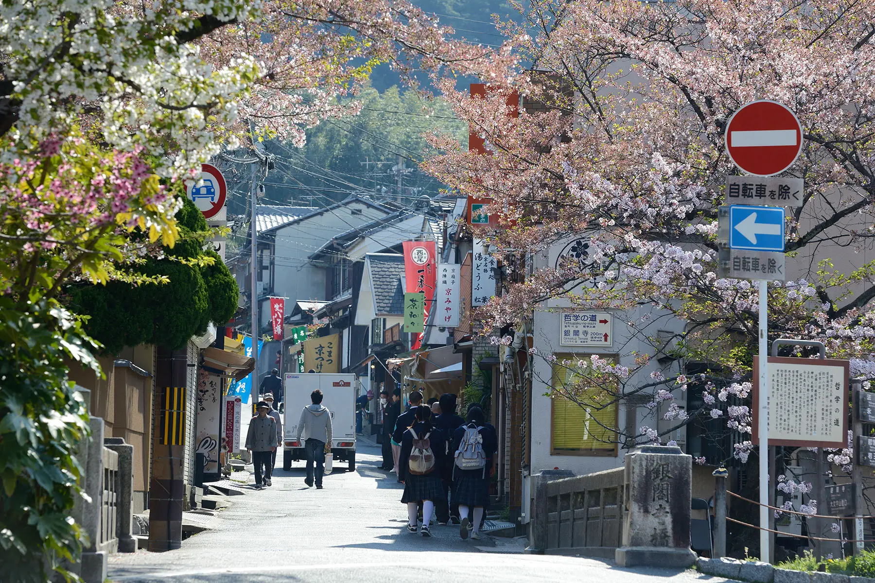 Residents walking through a street in Kyoto on a spring day.