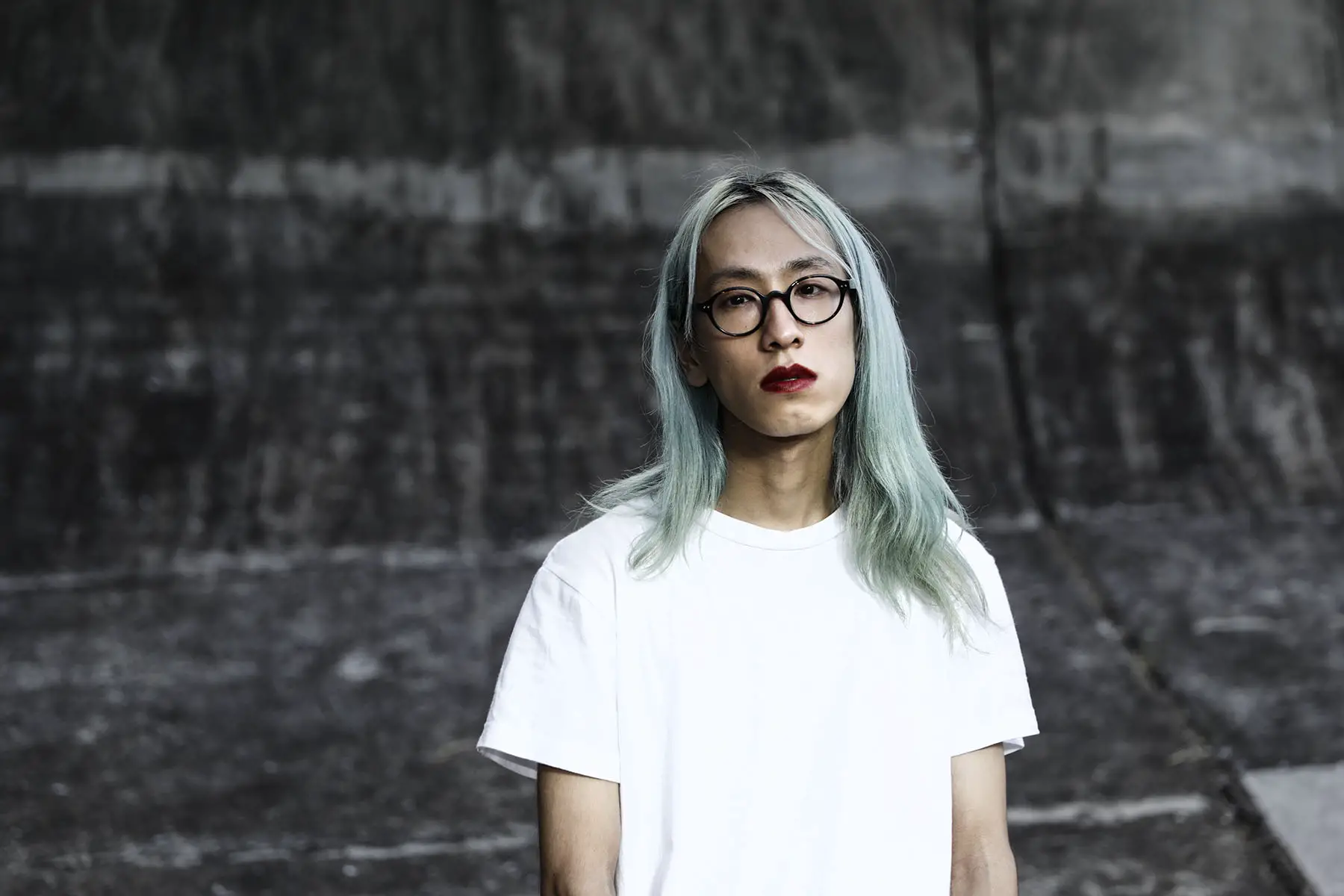 Portrait of a contemporary Japanese woman with greenish hair and glasses.