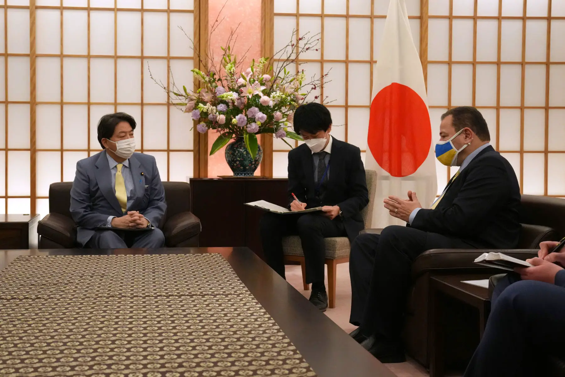Japan's Foreign Minister, Yoshimasa Hayashi, speaks with the Ukrainian ambassador to Japan, Sergiy Korsunsky, following the Russian invasion of Ukraine in 2022. A young person sitting in between them is taking notes.
