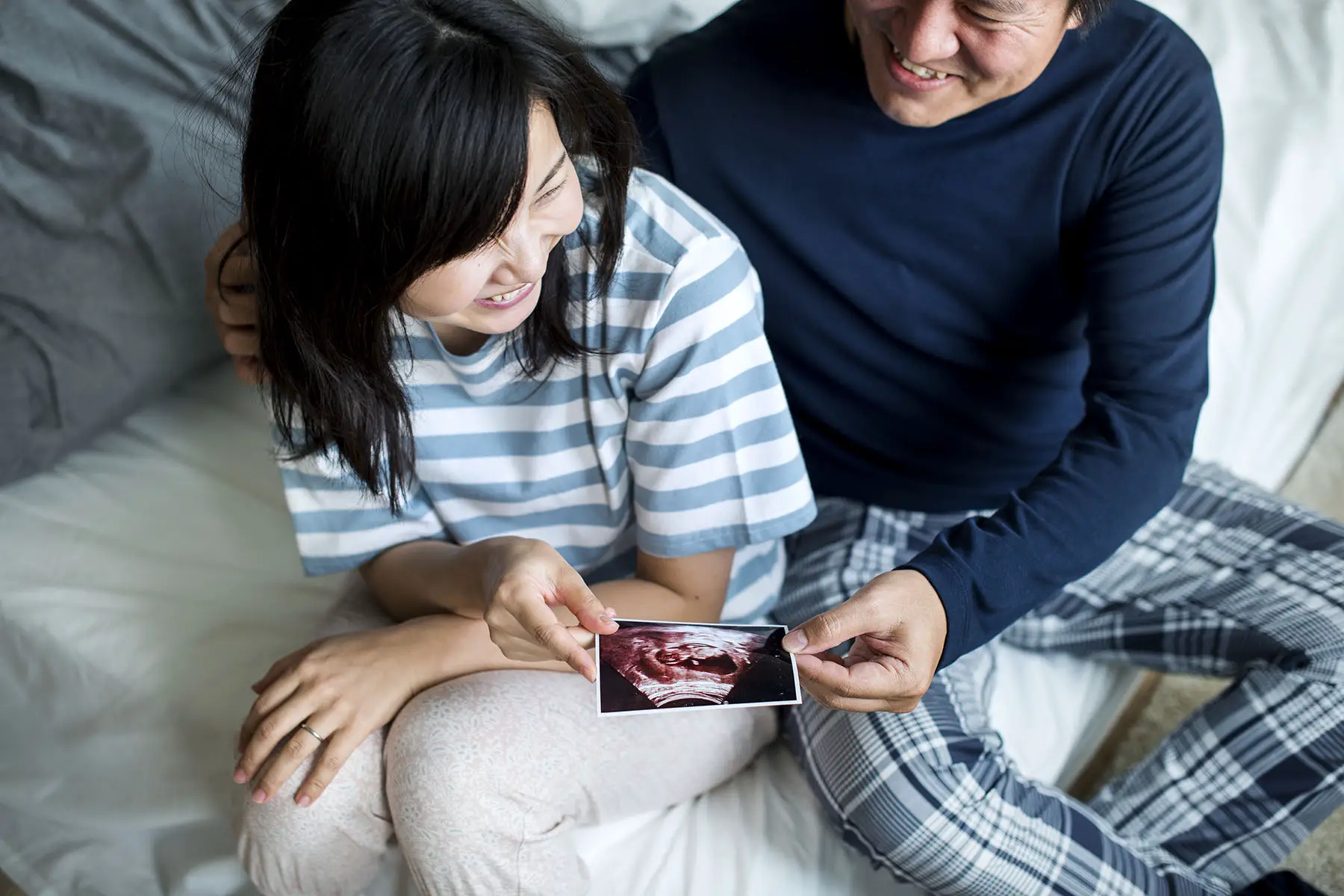 Happy couple holding a baby ultrasound photo.