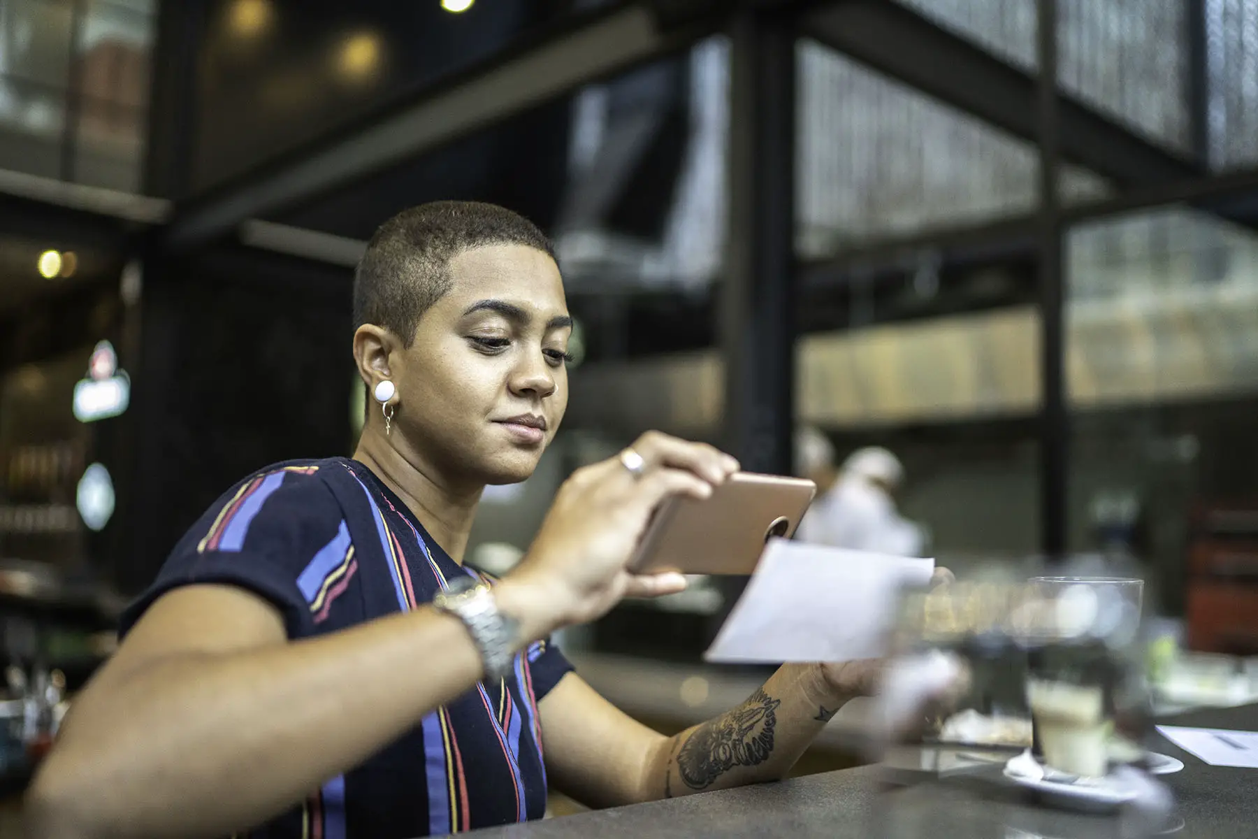 Young woman depositing check by phone in the cafe.