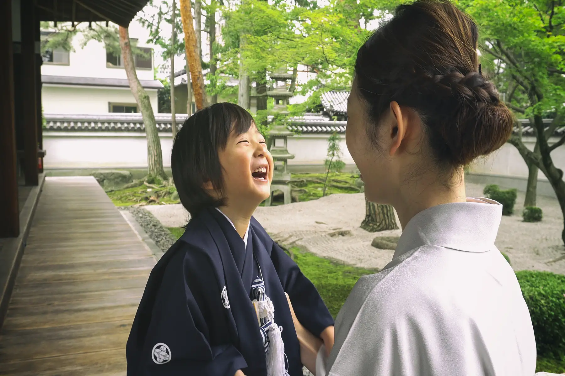 Little boy dressed in a traditional Japanese kimono for the Shichigosan Ceremony, laughs with his mother outside 