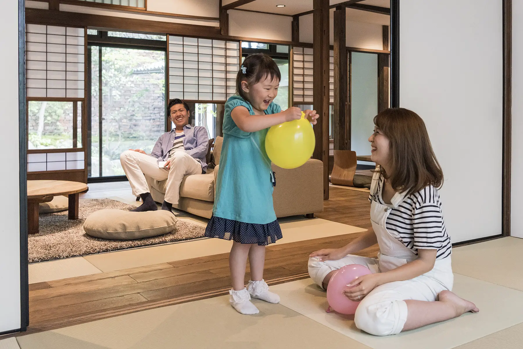 Japanese family in their home, with little girl playing with a yellow balloon
