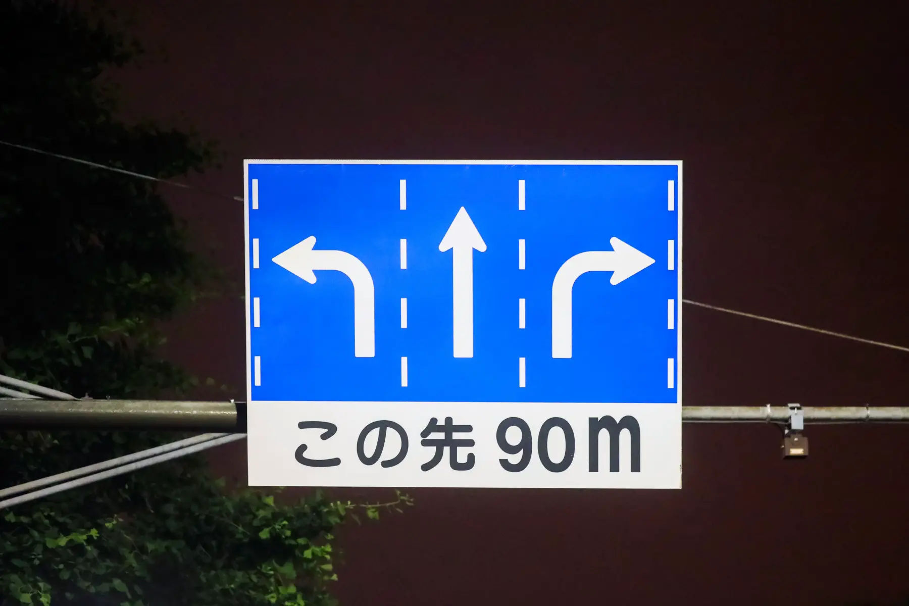 a blue and white Japanese road sign that indicates 90m ahead