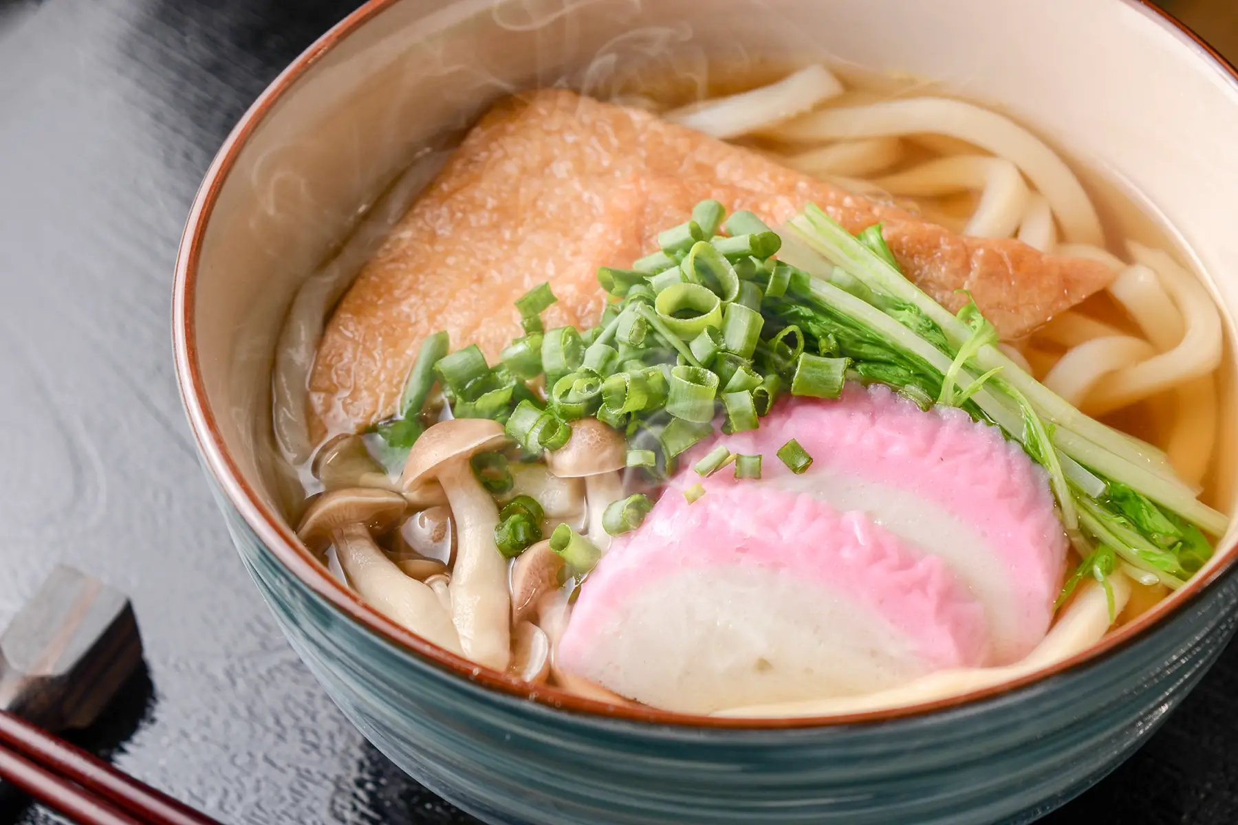 Kitsune udon: deep-fried tofu with udon noodles, scallions, fishcakes, and mushrooms