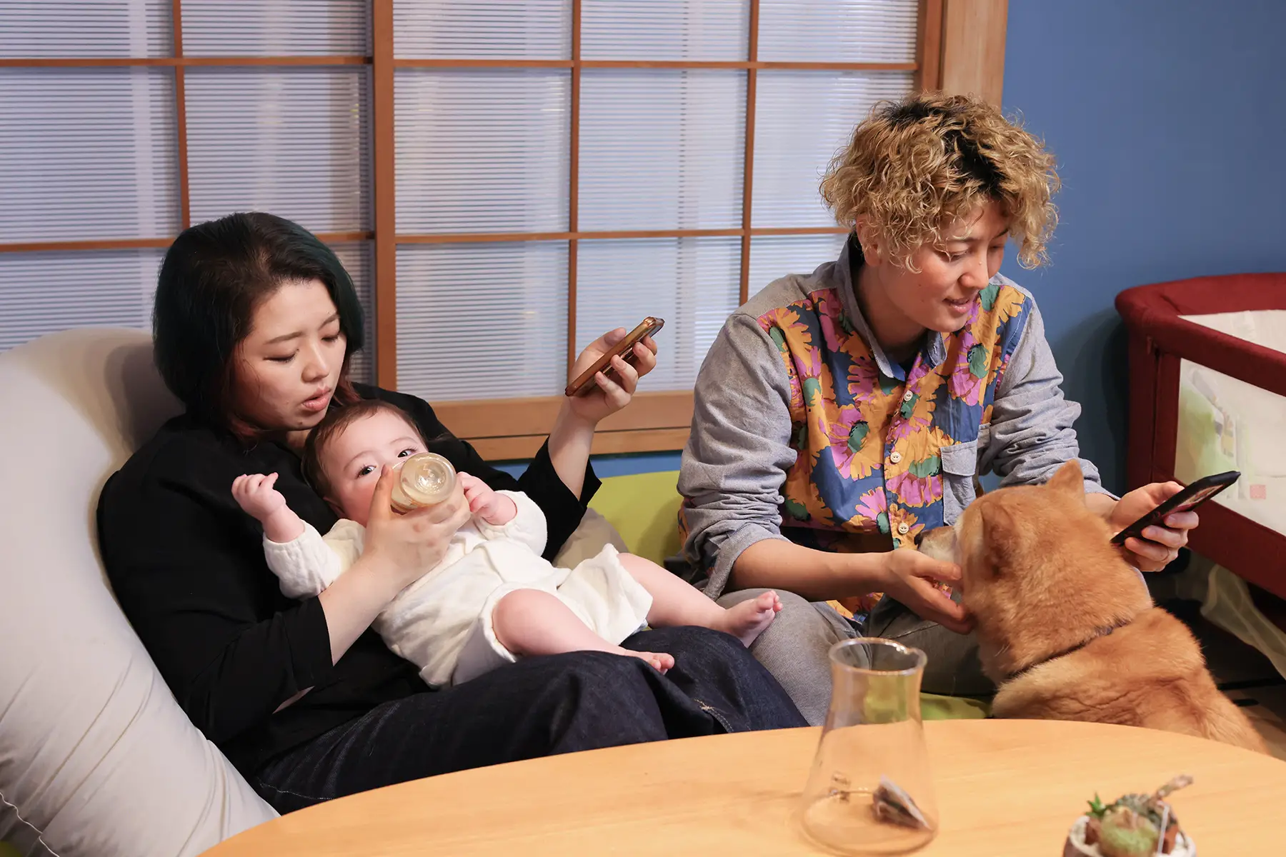 A couple from the LGBTQ community (two mums) bottle feeding their baby in their living room
