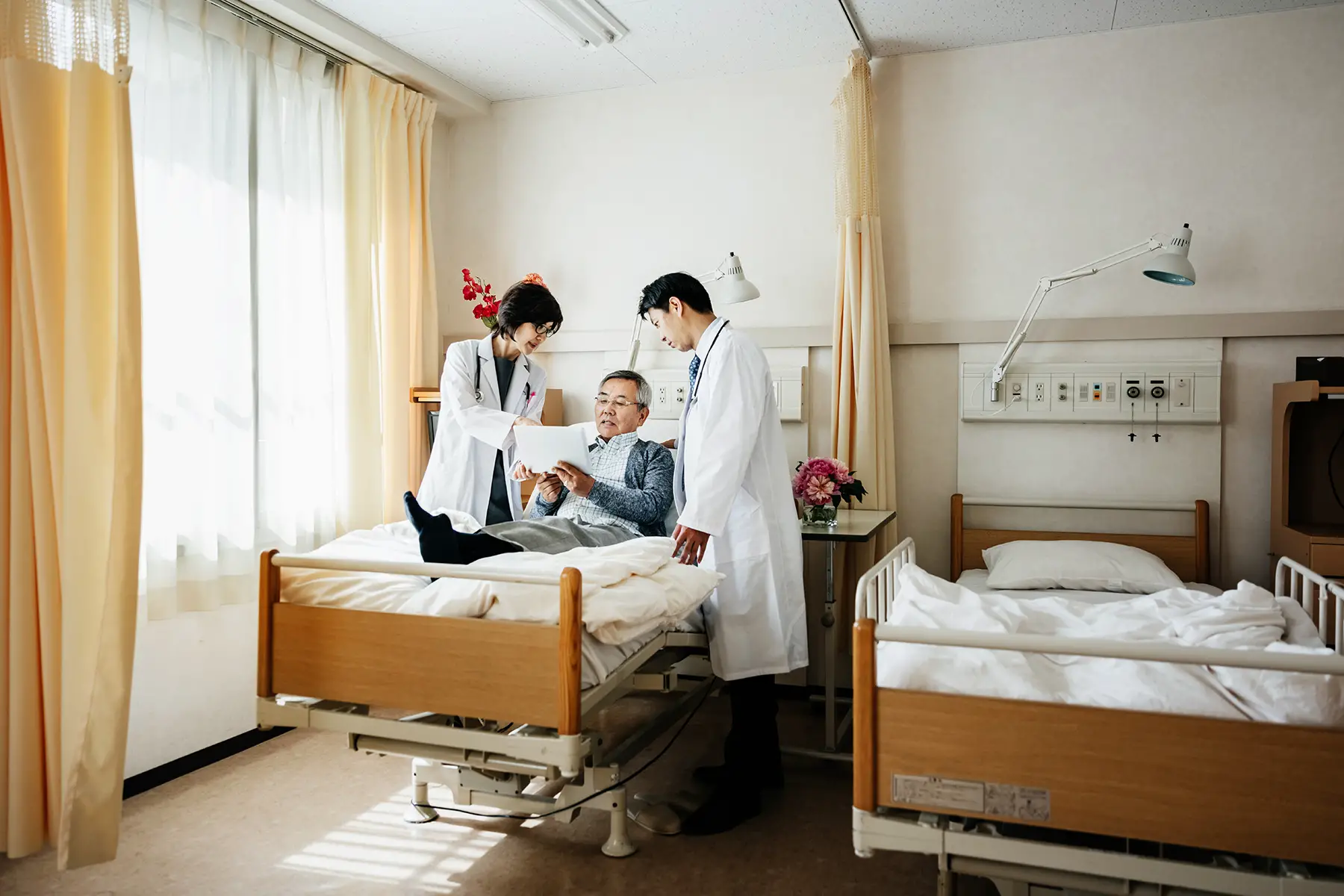 Man in hospital bed in Japan with two doctors