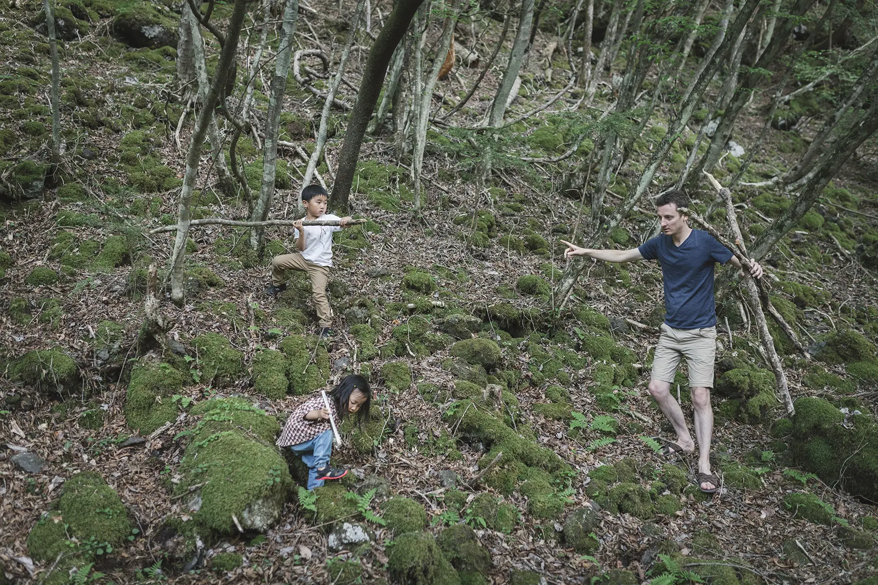 European dad with his Japanese children, playing in the woods