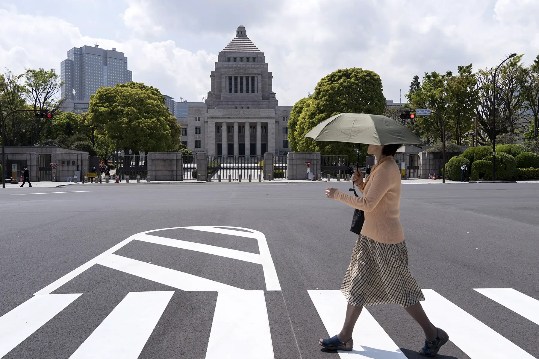Person with umbrella walks past The National Diet building in Tokyo