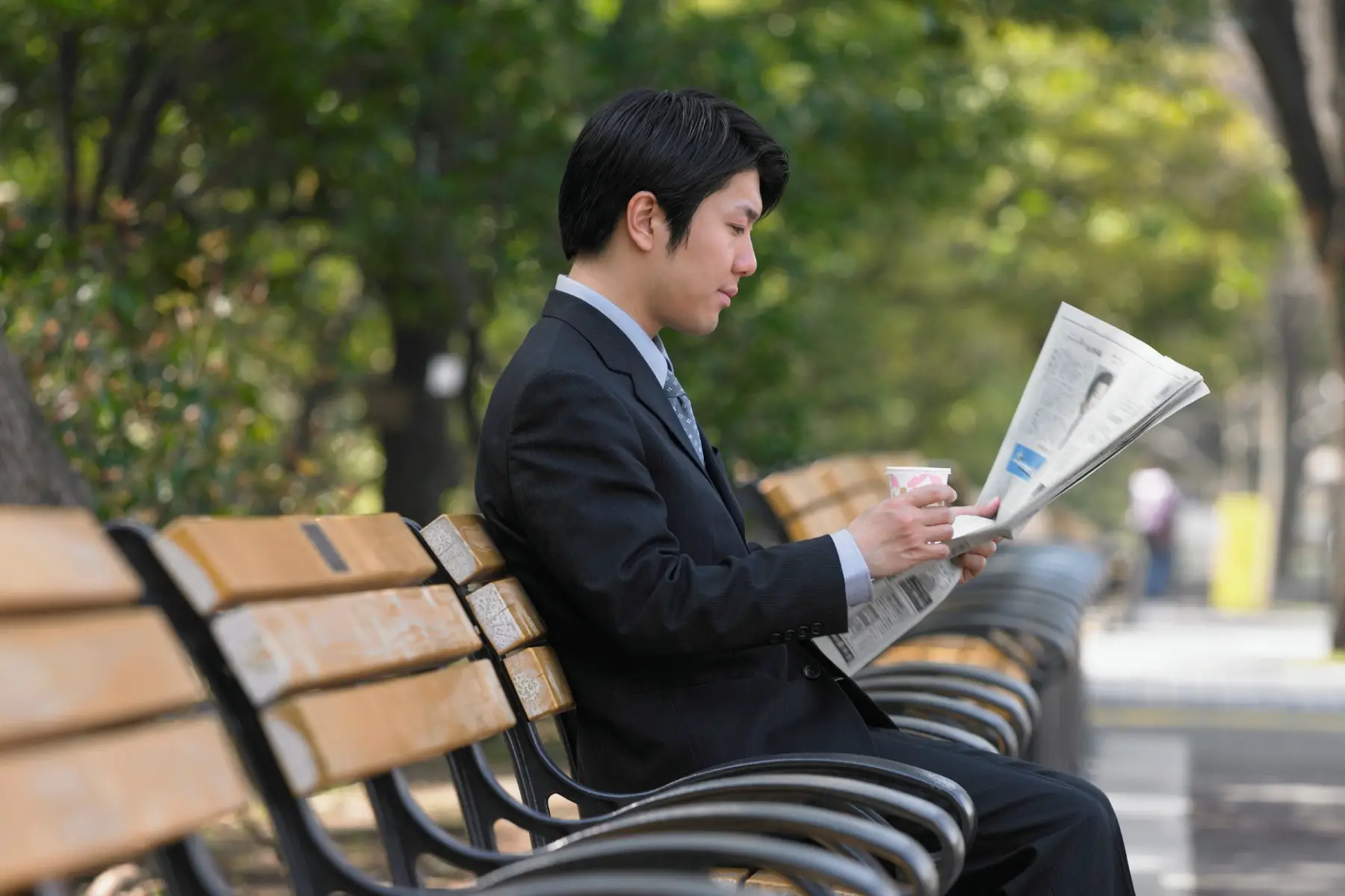 a Japanese businessman reading the newspaper on a park bench in Tokyo