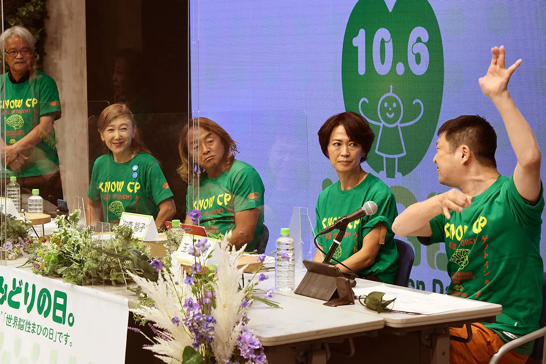 Members of NPO Get In Touch at a press conference. Panel are wearing green t-shirts