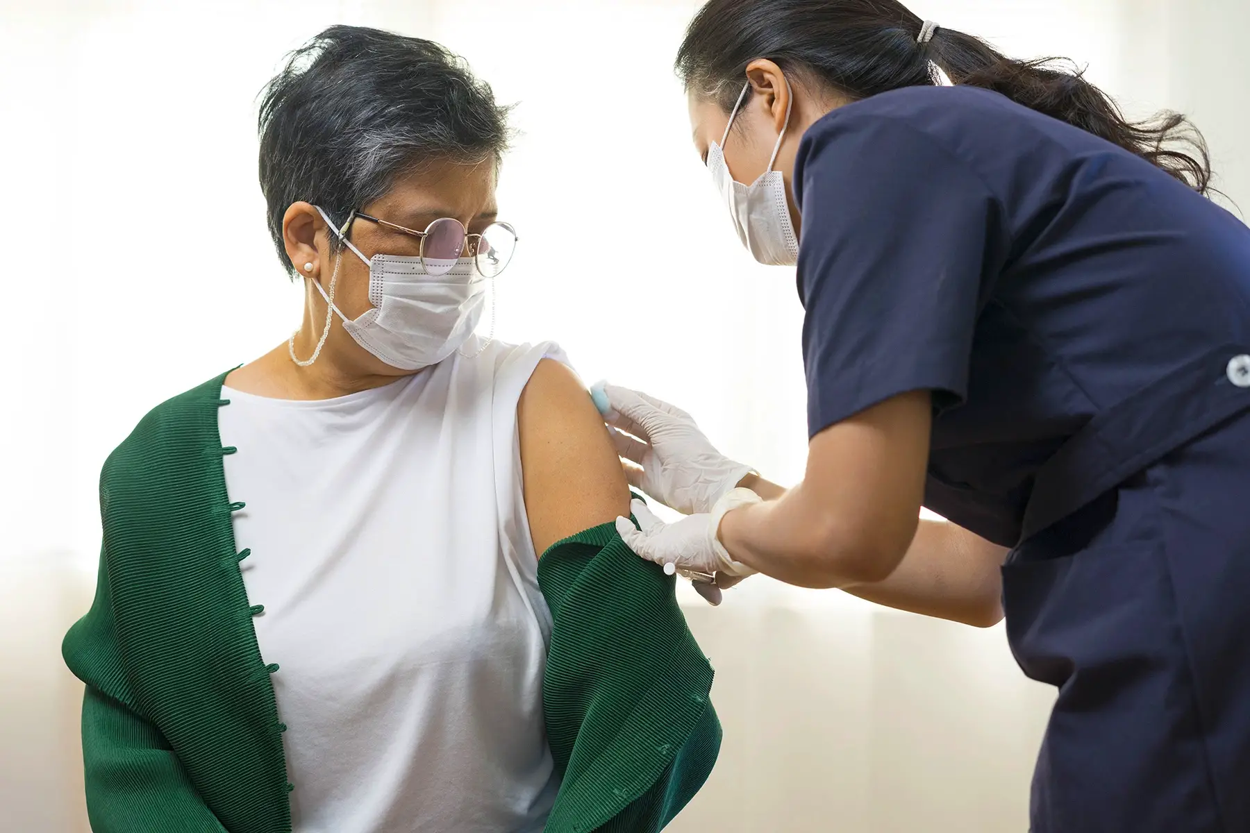 Nurse prepares an adult woman's arm for a vaccination