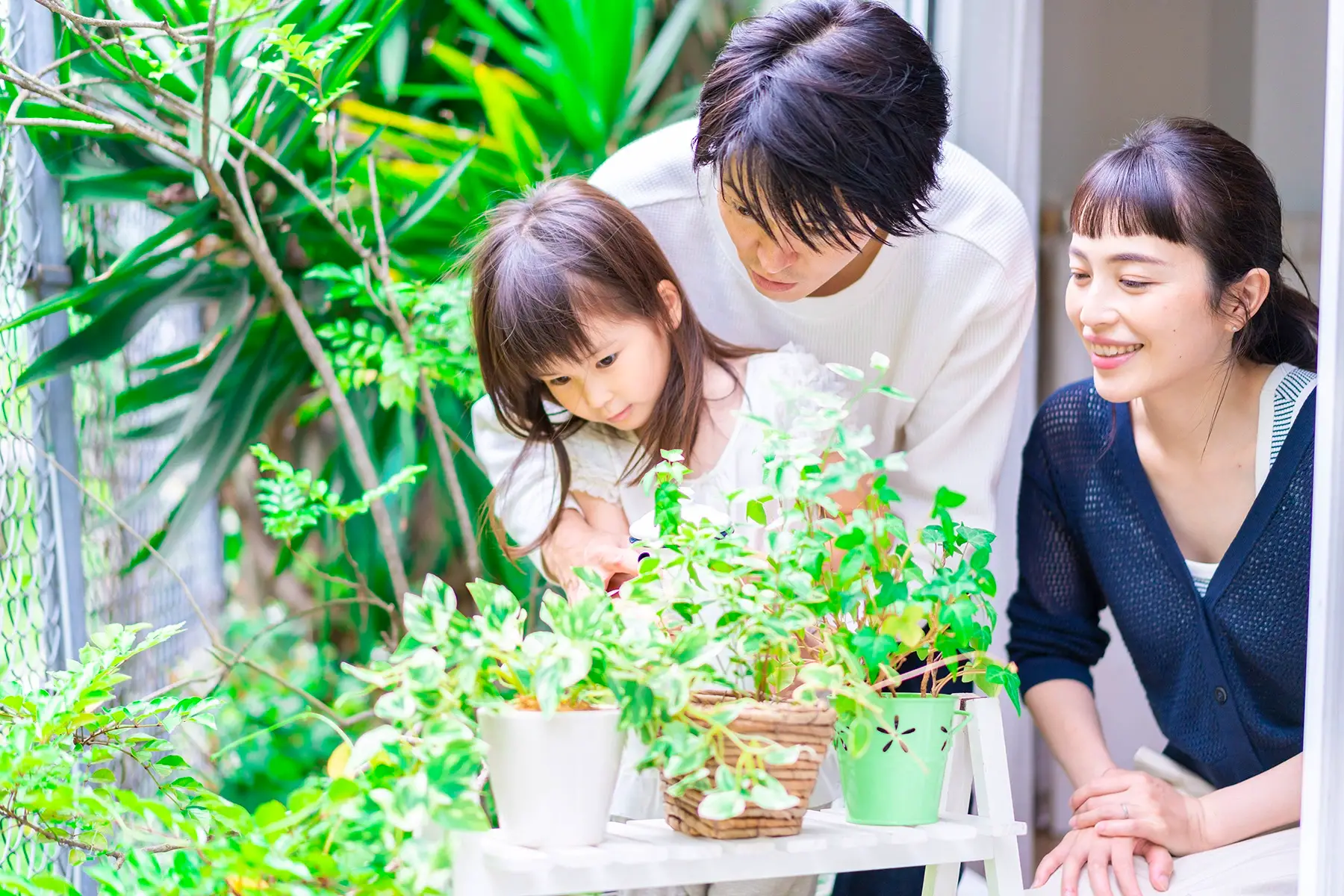 Parents with daughter caring for their potted plants
