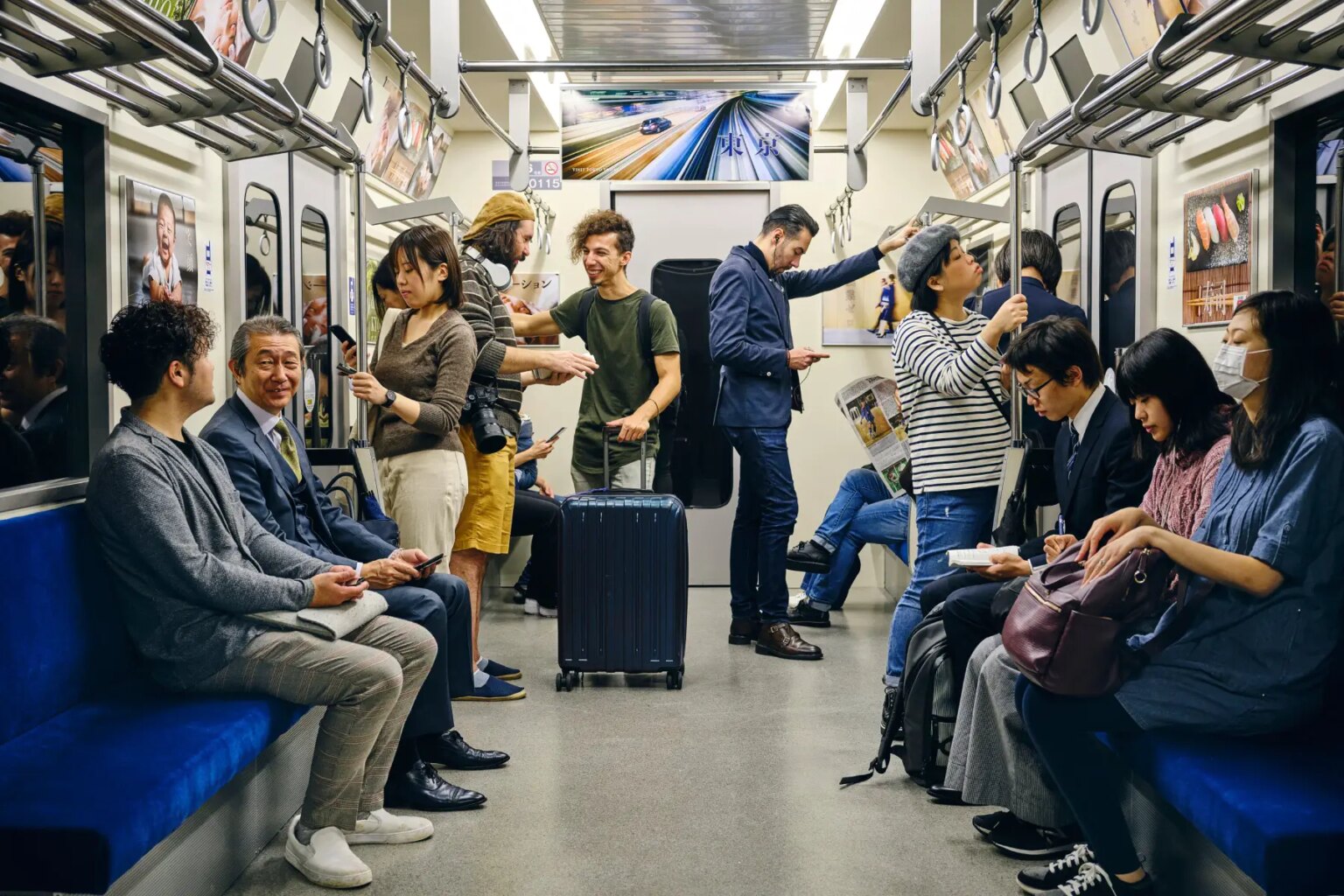A crowd of passengers sitting and standing in a Japanese subway train