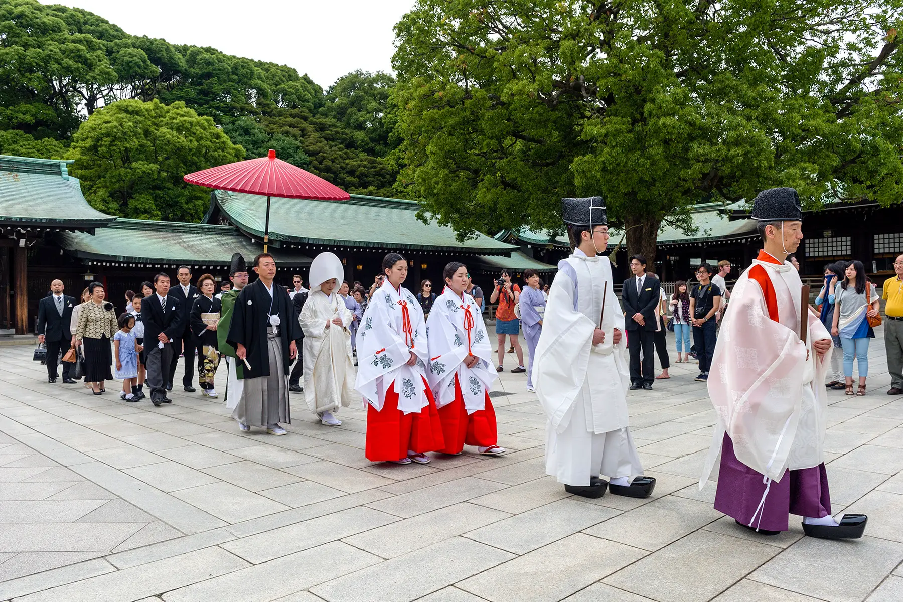 A procession through a temple of people wearing traditional Japanese wedding outfits