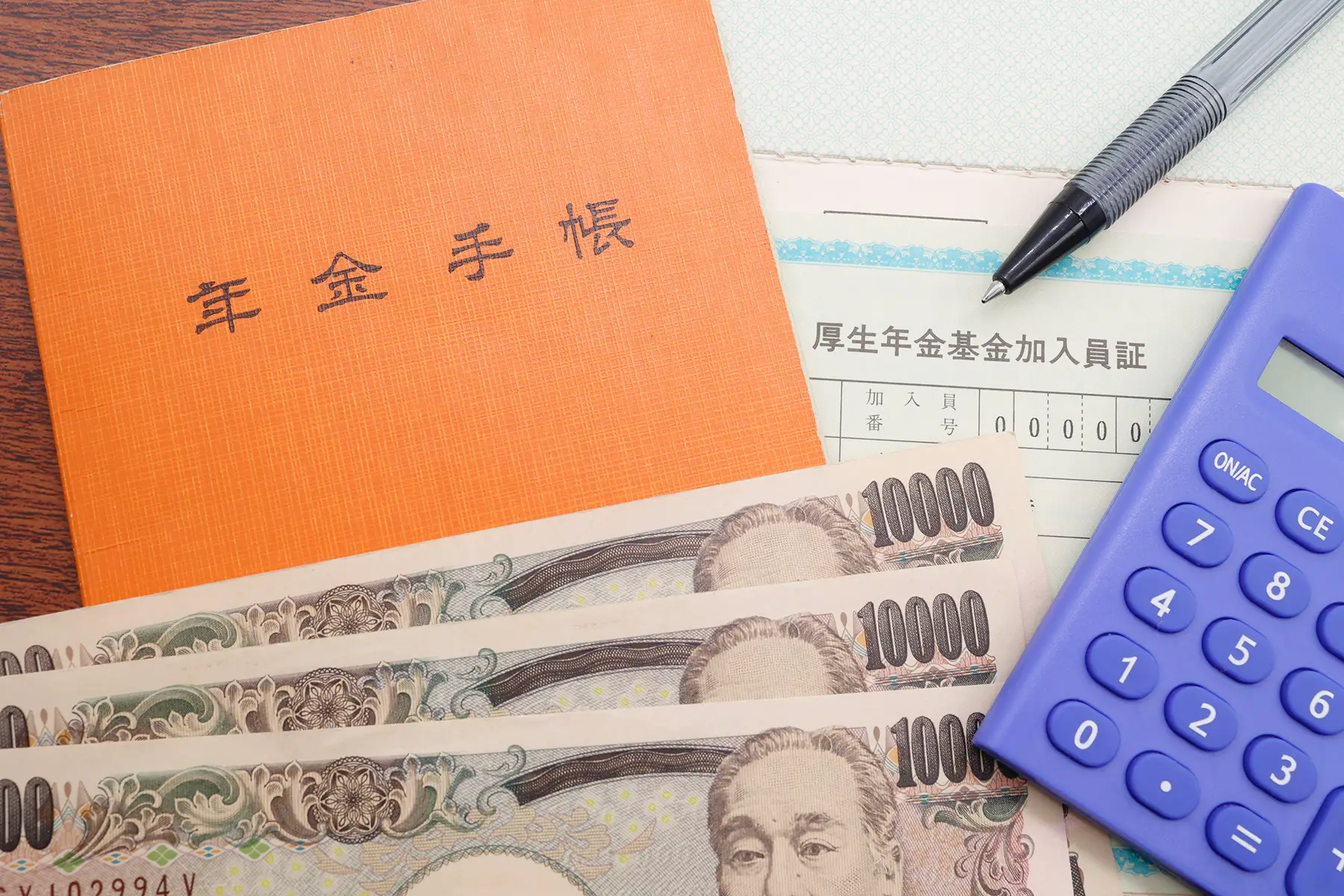 An orange booklet for pensions, ¥3,000 in notes, a calculator, and a social security form on a desk