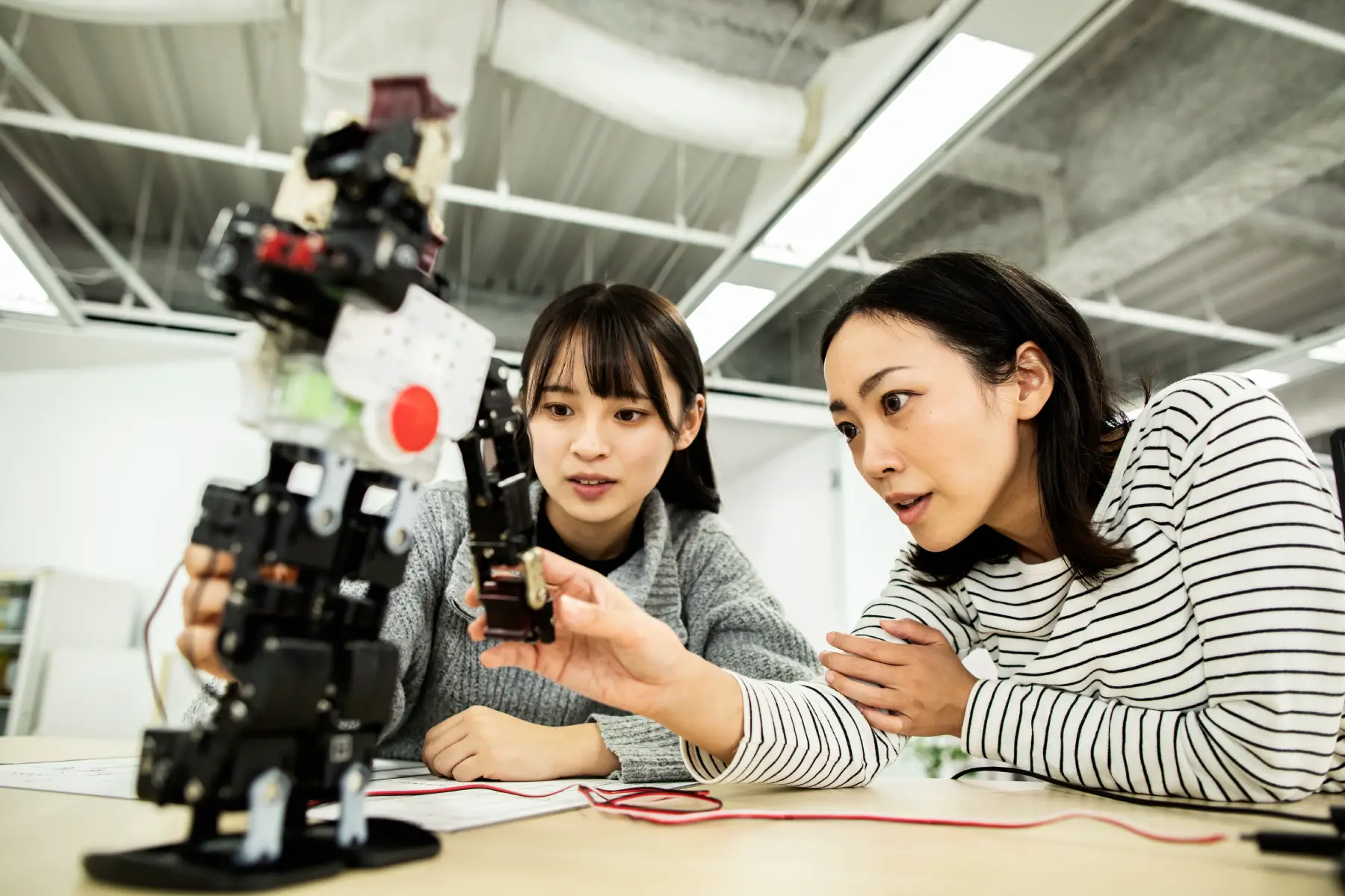 Two female students experiment with a robot prototype
