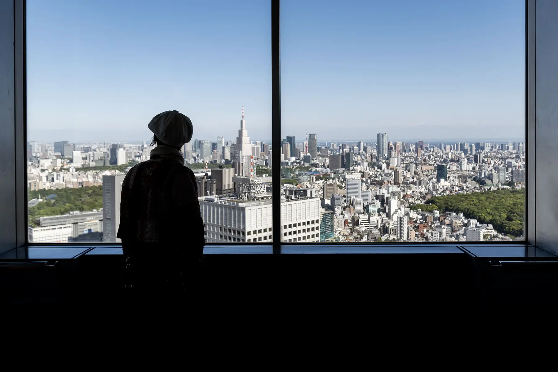 Silhouette of person looking out a big window on the observation Decks of Tokyo Metropolitan Government Building, Shinjuku, Japan. 