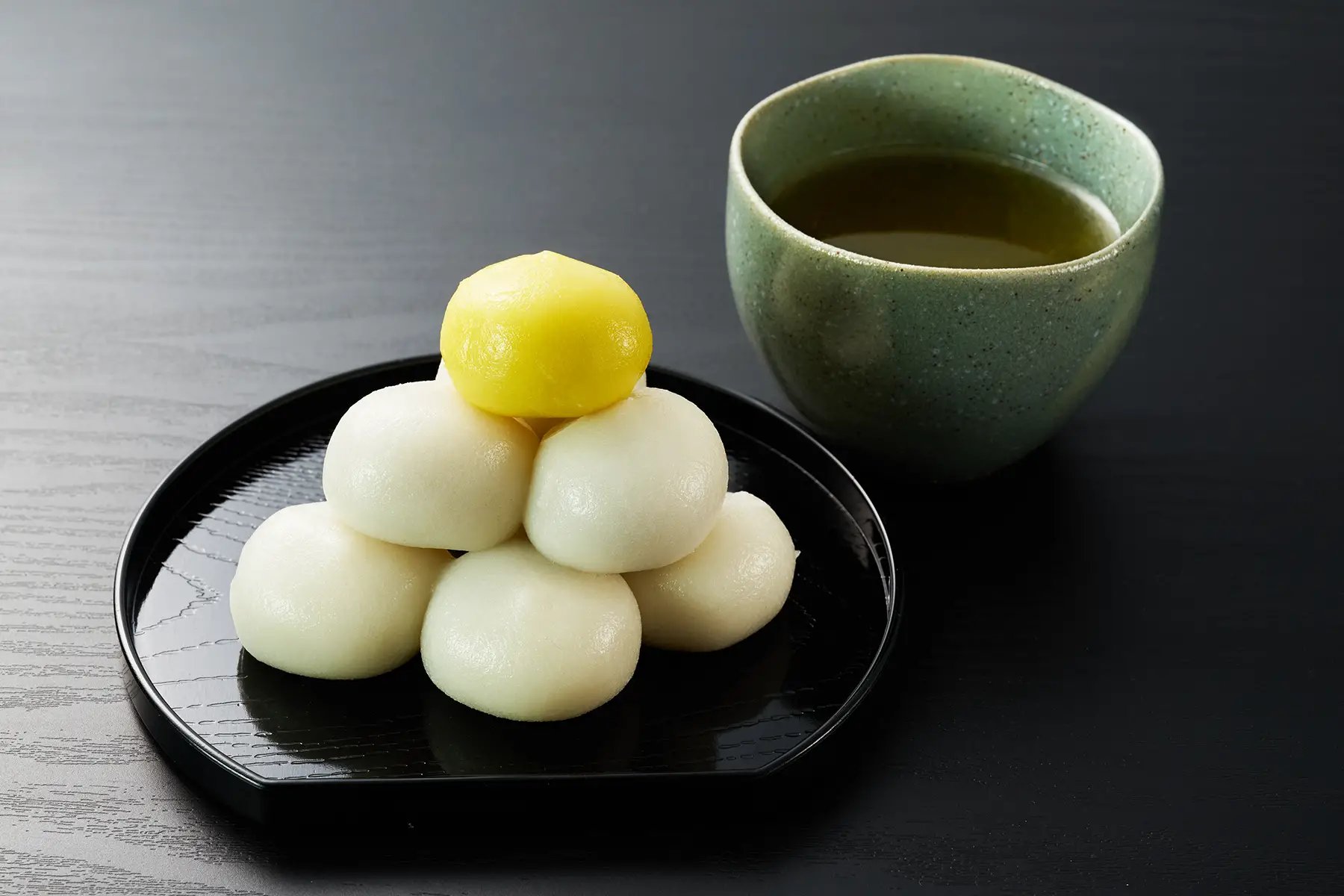 Spherical rice dumplings on a plate next to a cup of tea