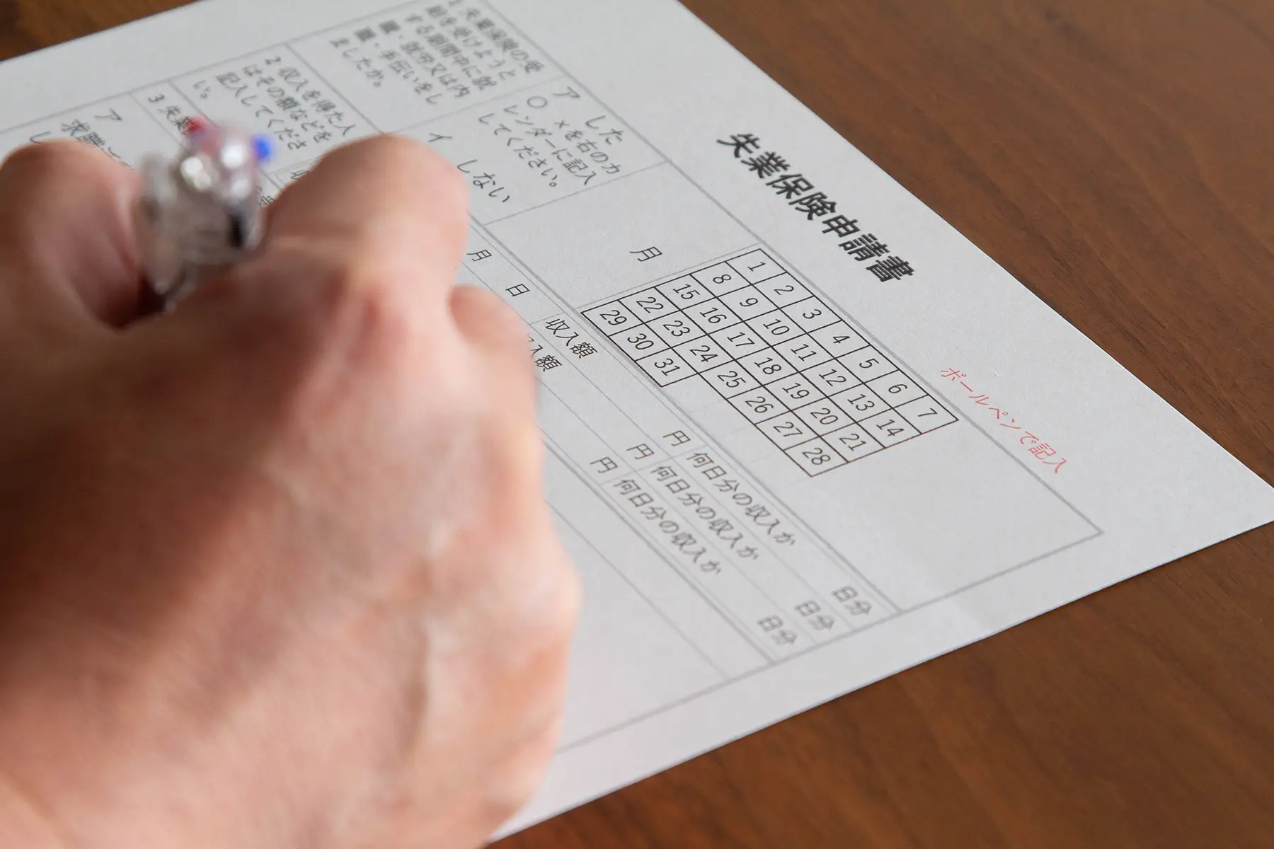 Close-up of a person's hand filling out an unemployment form