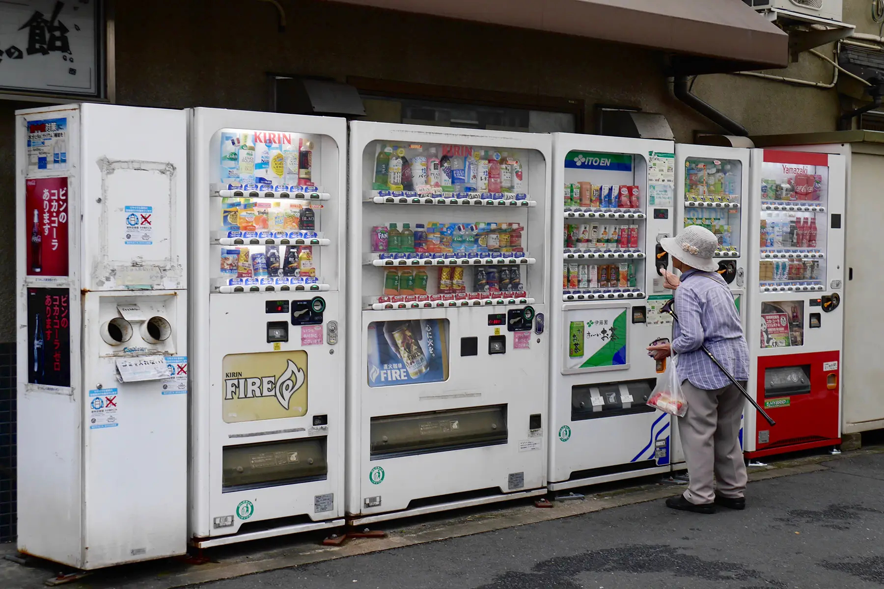 A women buys a drink from a row of vending machines in Tokyo, filled with plastic bottles and containers