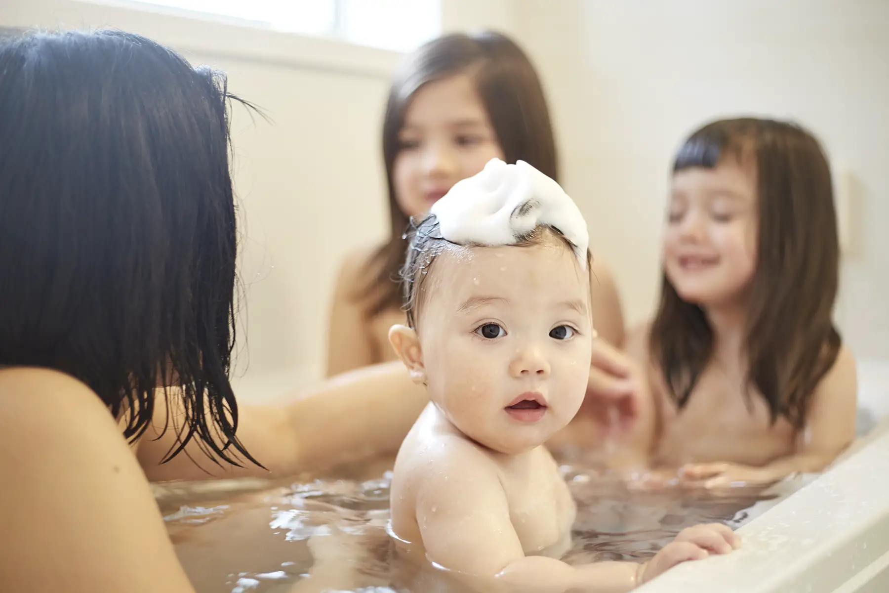 Children in bath, baby has bubble bath on their head