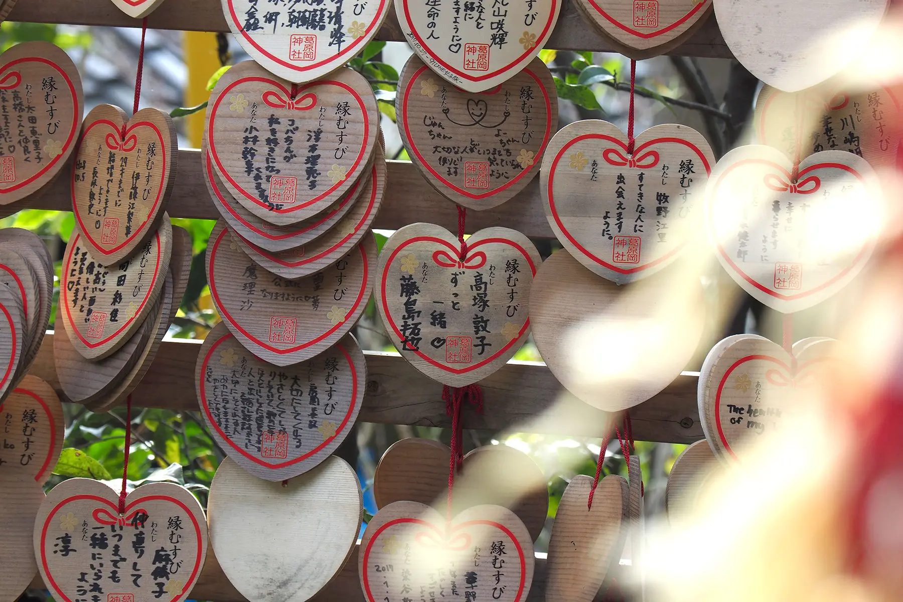 Wooden heart-shaped tablets covered in writing, hanging on a fence 