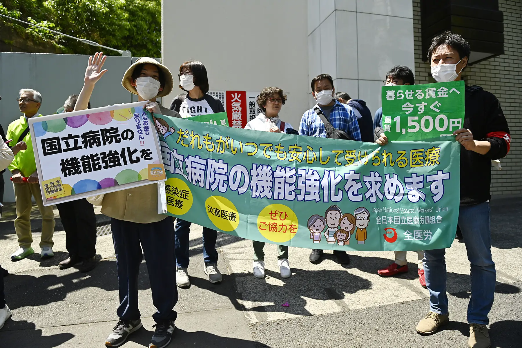 Workers protesting, holding a banner and signs in Japanese