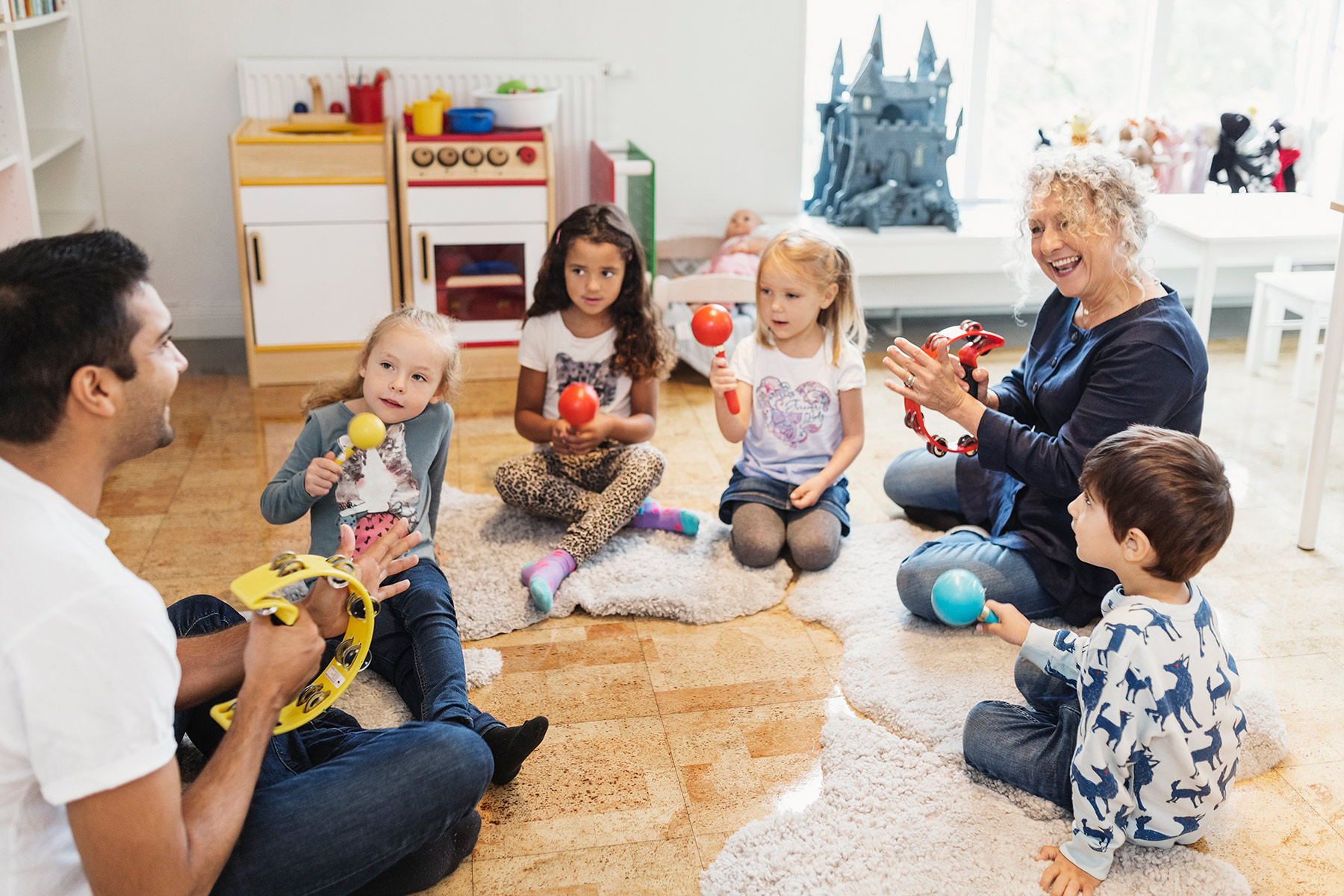 Children playing musical instruments with two teachers in a preschool