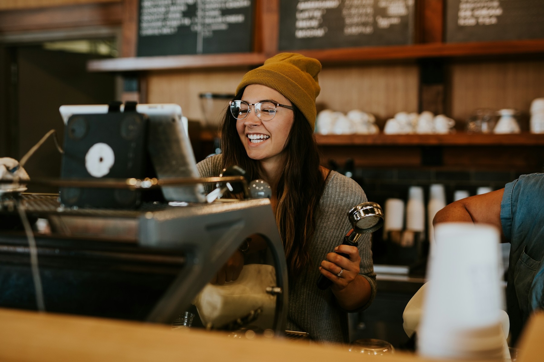 A barista smiles while using the espresso machine to make a drink for a customer