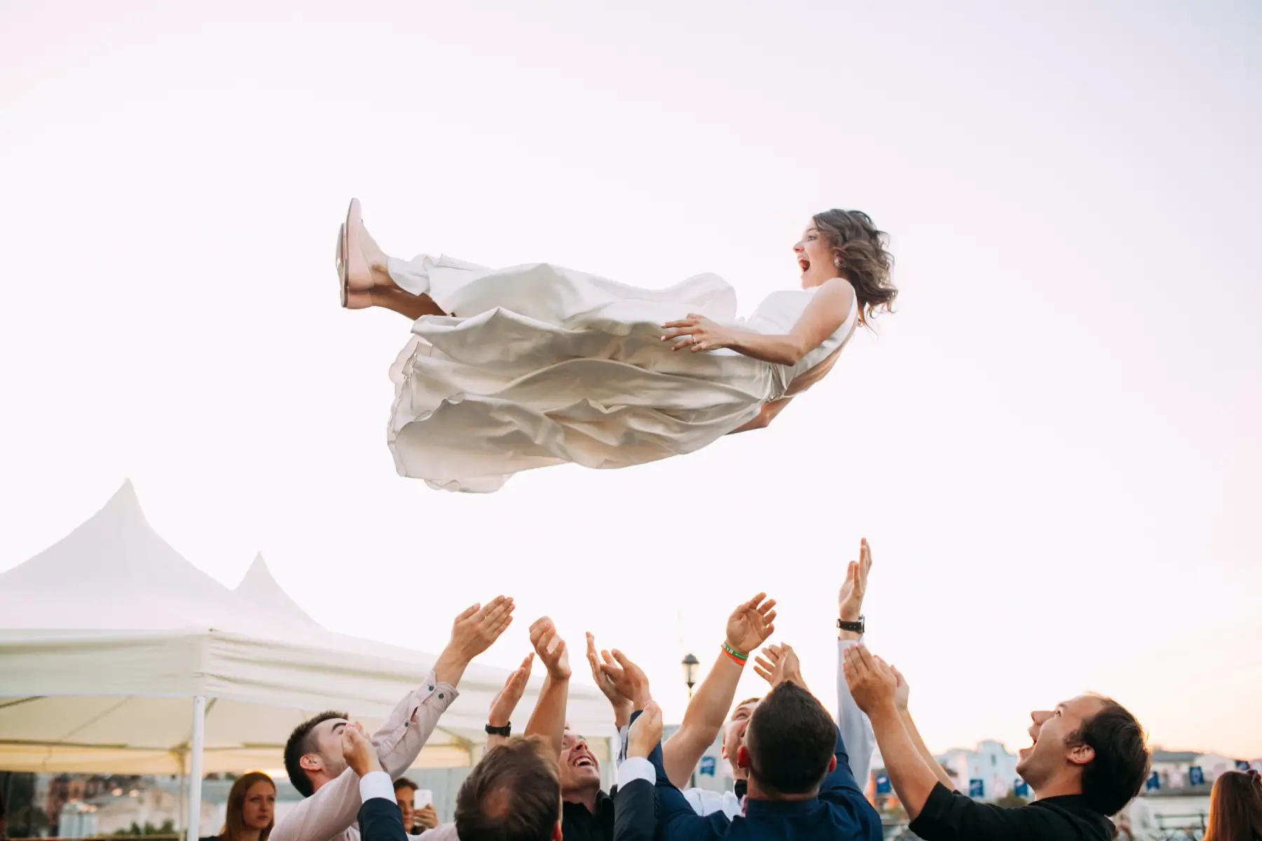Bride thrown in air at ceremony, part of a tradition.