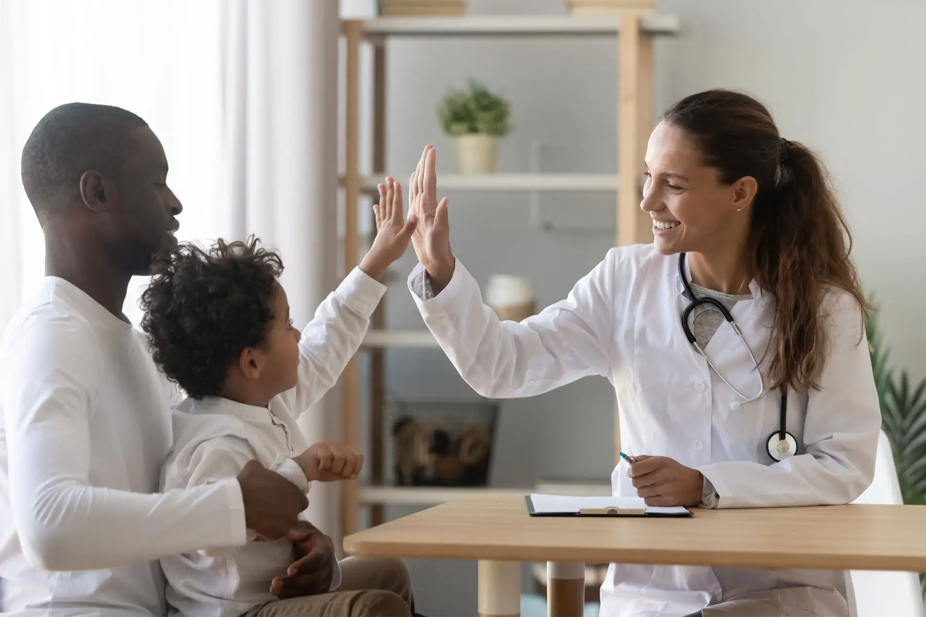 a family doctor high-fives a young patient