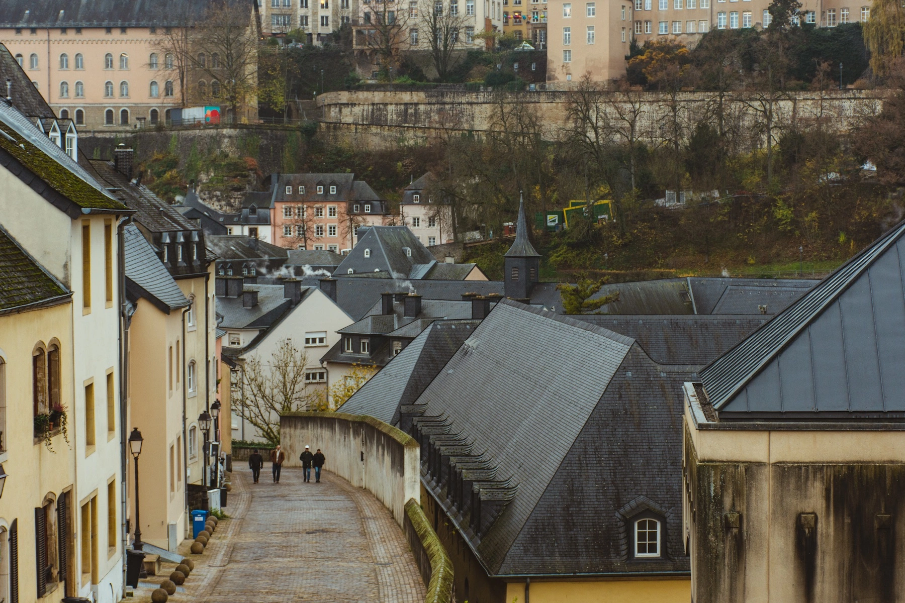 From a distance, four friends walk along the streets of Luxembourg City, Luxembourg on a cloudy winter day